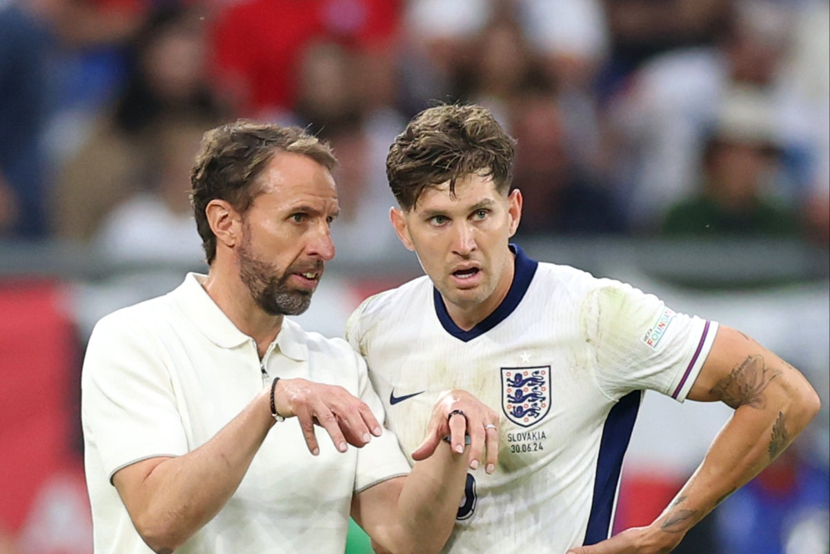 Stones (right) discussing tactics with manager Gareth Southgate during the win over Slovakia