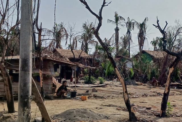 <p>A woman cooking next to destroyed houses following fighting between Myanmar’s military and the Arakan Army in Minbya township of Rakhine state on 21 May 2024</p>