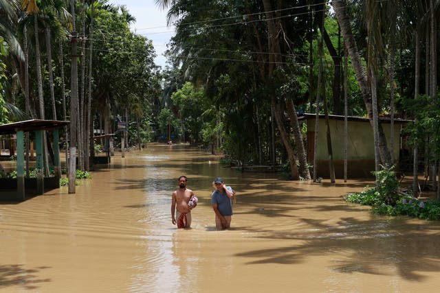 <p>People wade through a flooded street in Nagaon district of Assam, India </p>