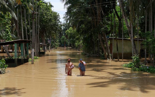 <p>People wade through a flooded street in Nagaon district of Assam, India </p>
