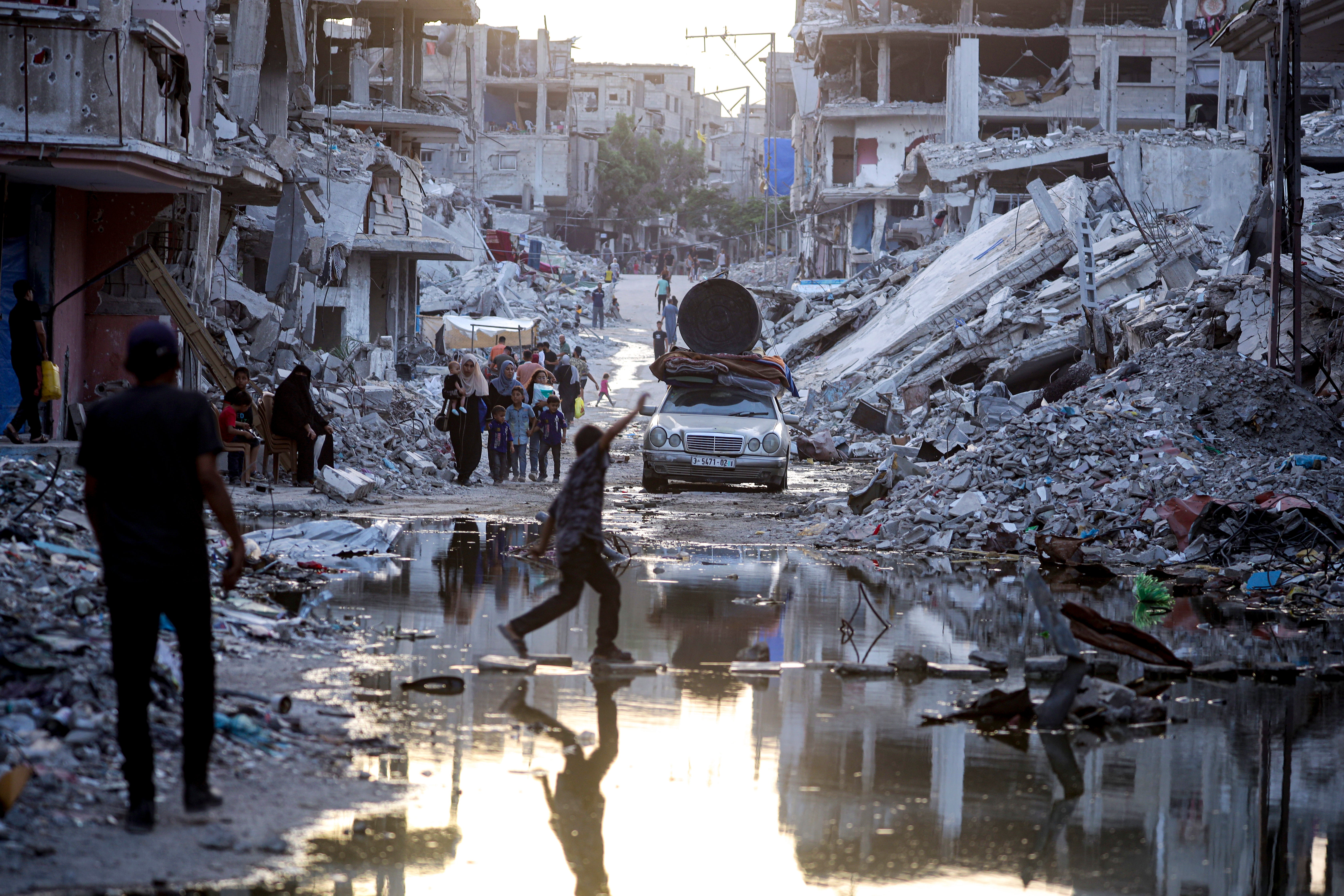 Palestinians displaced by the Israeli air and ground offensive on the Gaza Strip, walk past sewage flowing into the streets of the southern town of Khan Younis