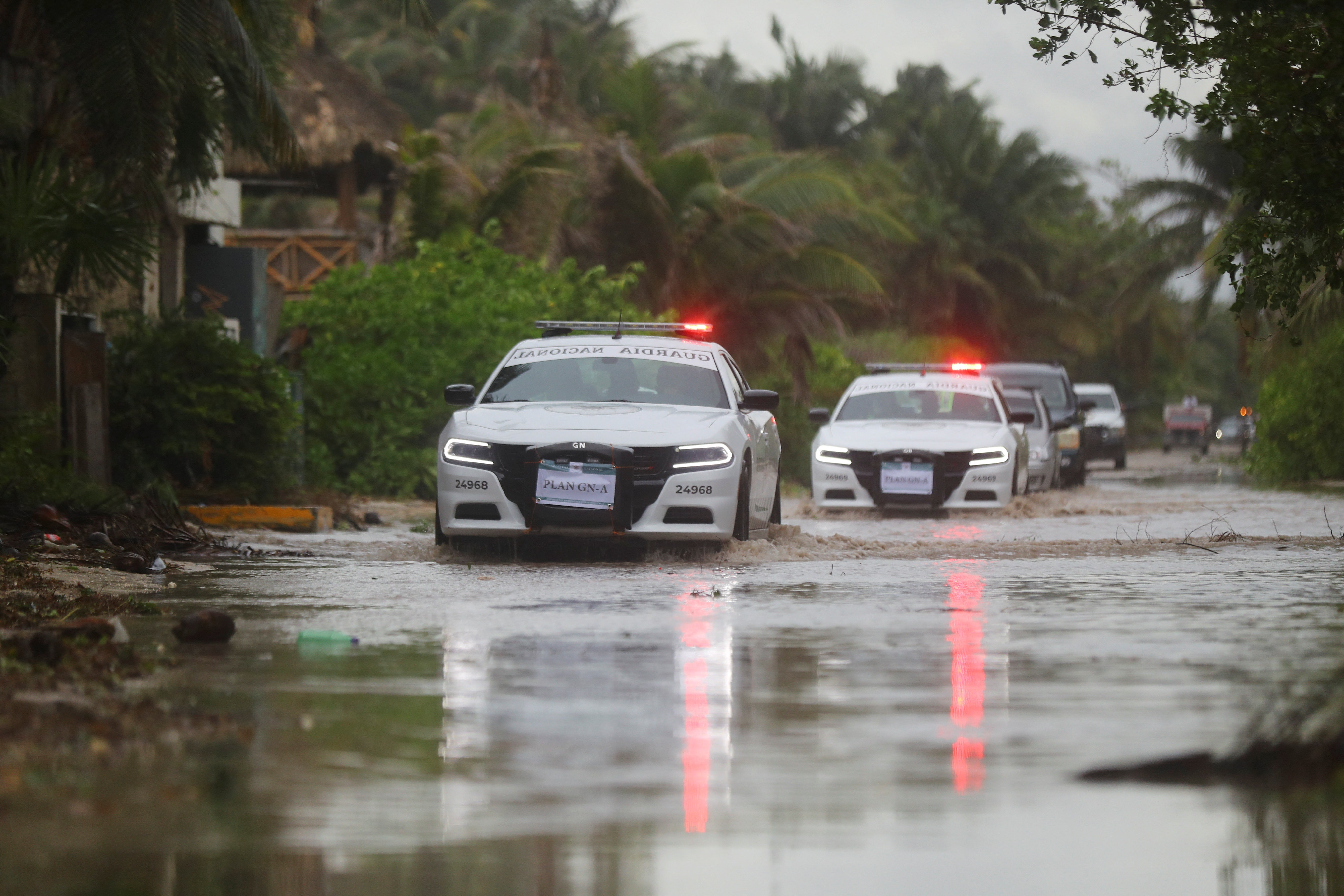 National Guard vehicles drive through flooded streets in Tulum, Mexico on Friday