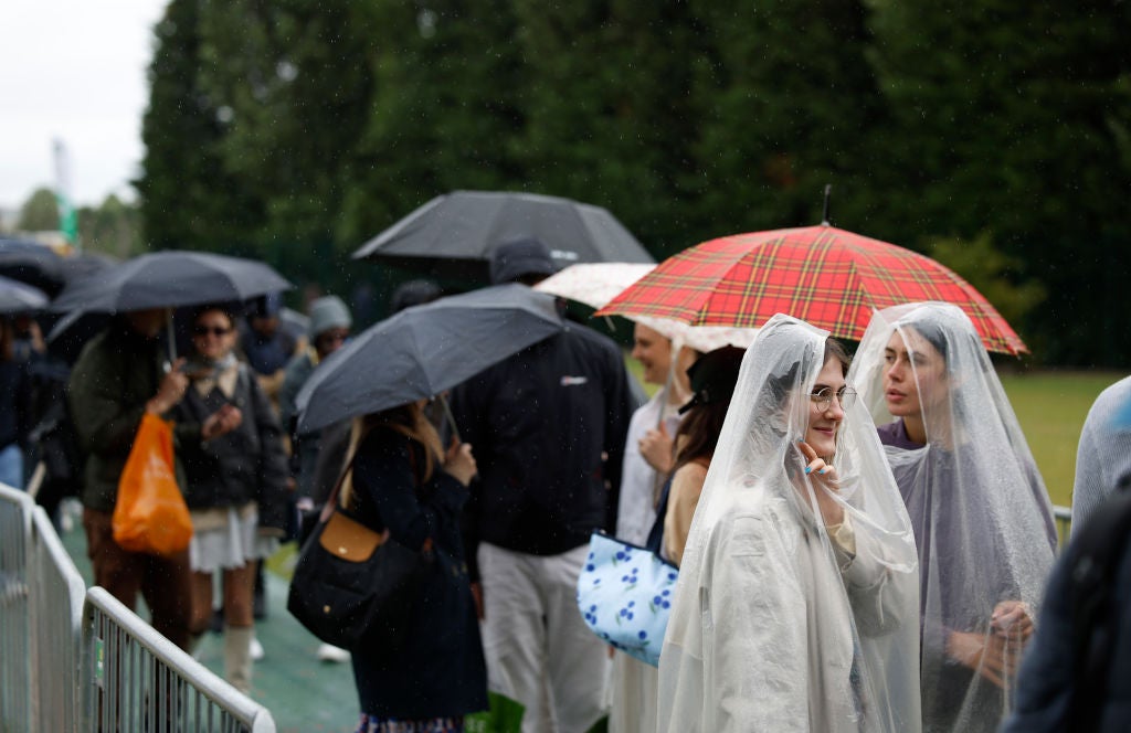 Fans shelter as they wait in the Wimbledon queue