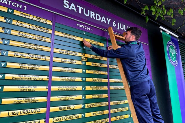 A member of the ground staff removes the names of Andy Murray and Emma Raducanu from the order of play during day six of the Championships in Wimbledon (PA Wire)