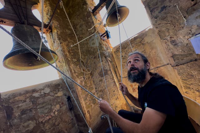 <p>Sitting in a chair with ropes looped around both feet and hands, Joan Carles Osuna, a student of the Vall d'en Bas School of Bell Ringers, performs playing all four bronze bells at the church bell tower of the12th-century Sant Romà church, at the village of Joanetes, about two hours north of Barcelona, Spain</p>
