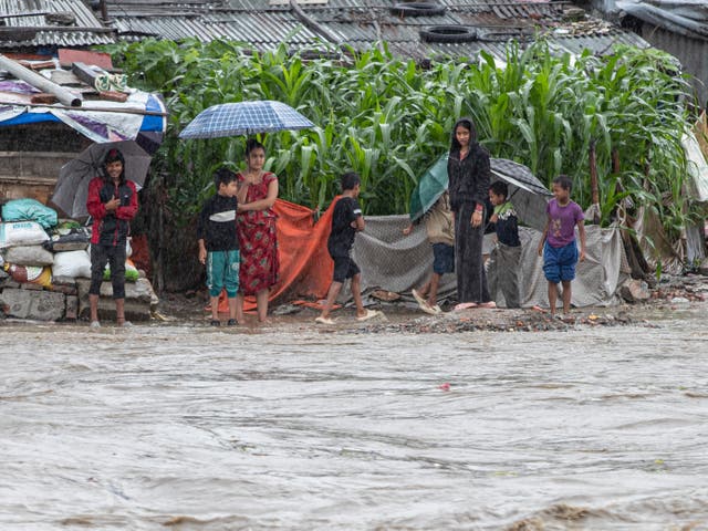 <p>People stand near the flooded temple area as the Hanumante River rises after torrential rains in Kathmandu, Nepal</p>