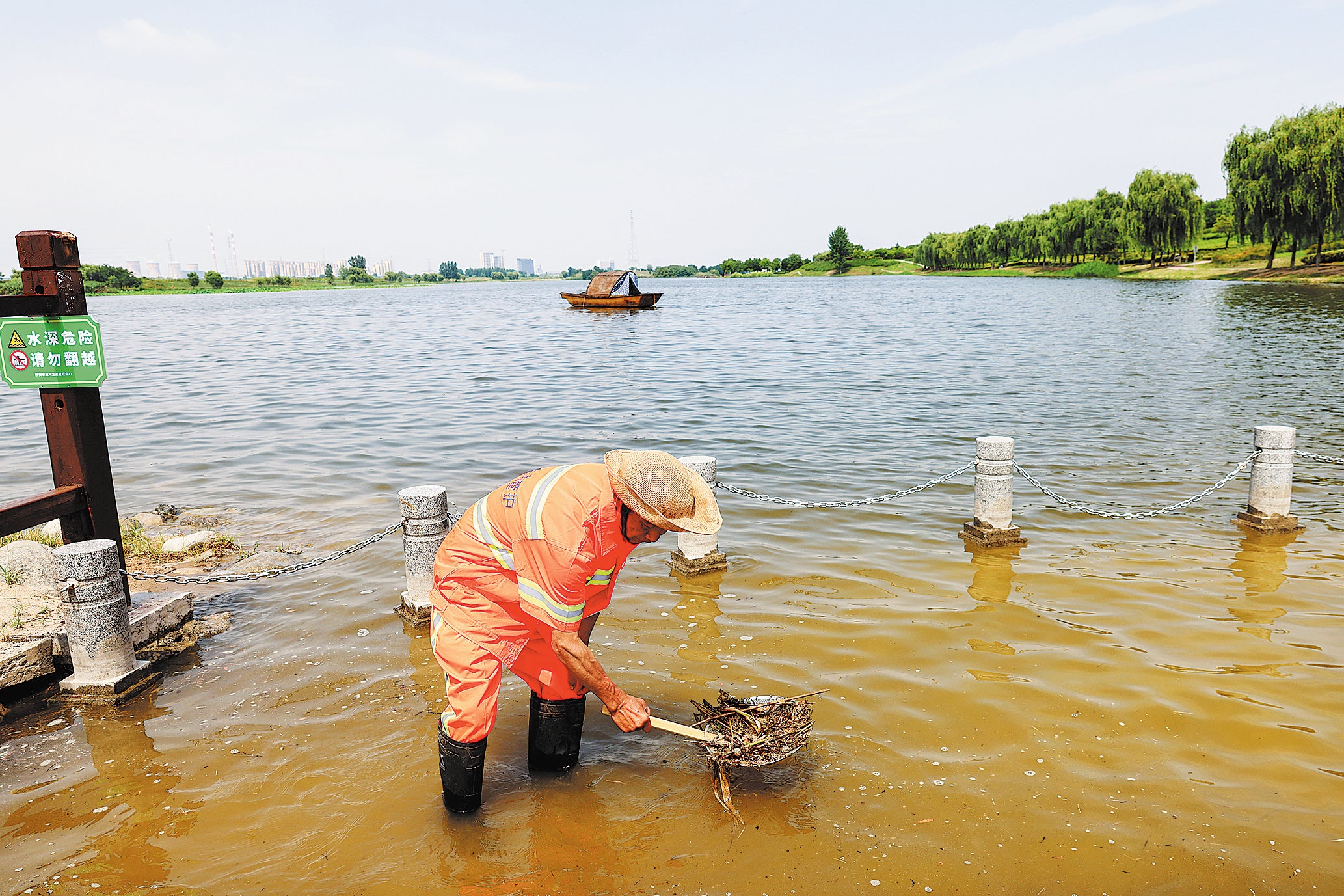 A sanitation worker cleans tree branches from Xi’an Lake in Xi’an, Shaanxi province, in June