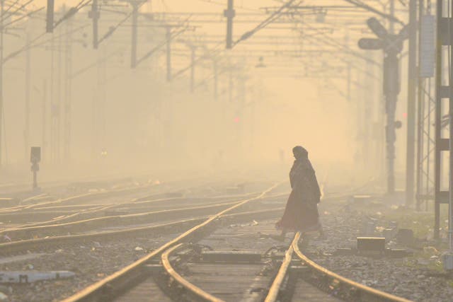 <p>A woman walks across a railway track amid smog on on the outskirts of Jalandhar, India, on 21 December 2023</p>