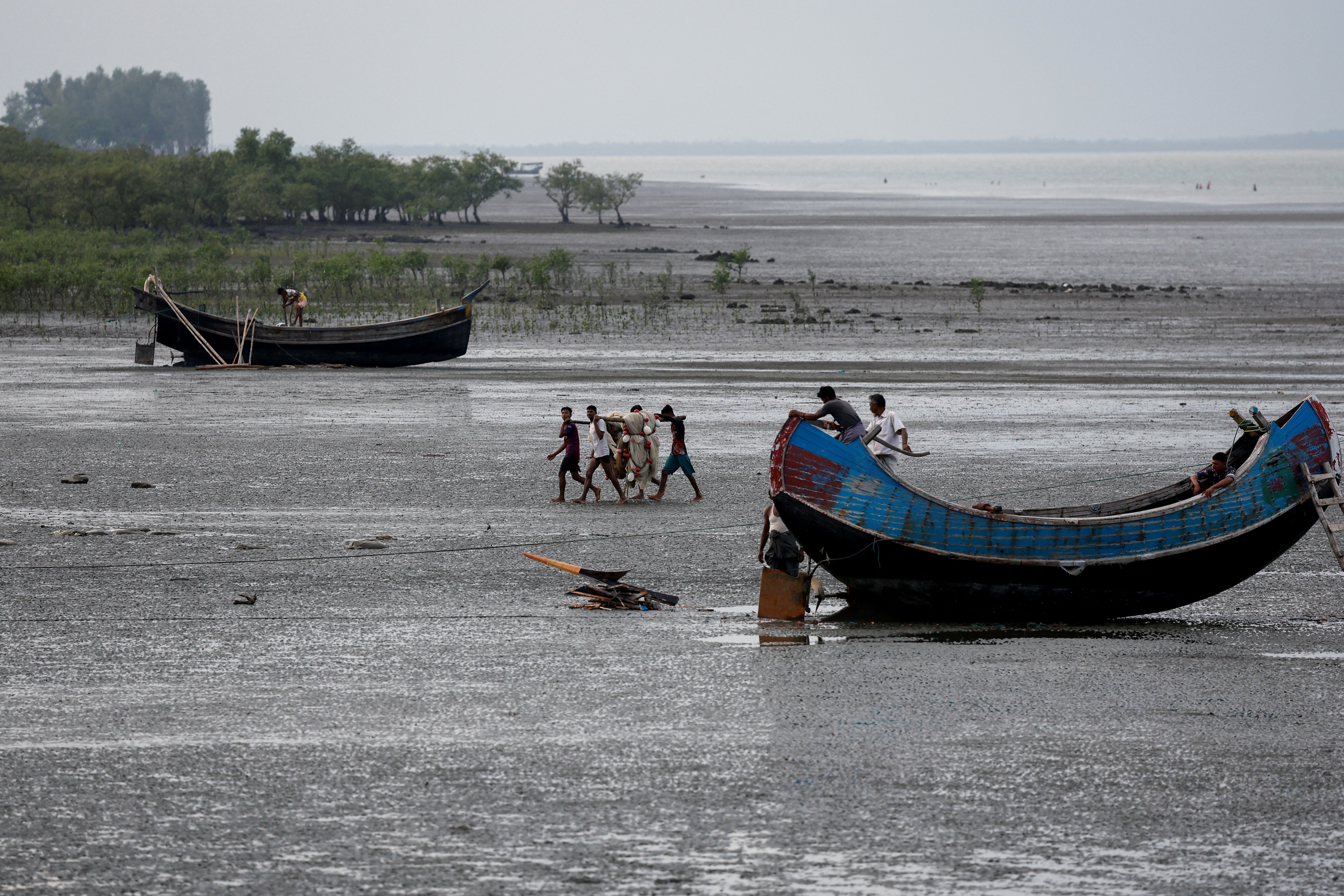 <p>Fishermen carry a fishing net at the bank of Naf river, in Teknaf area of Cox's Bazar</p>