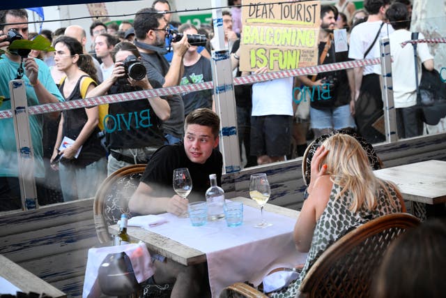 <p>Demonstrators put symbolic cordon on a bar-restaurant window during a protest against mass tourism </p>