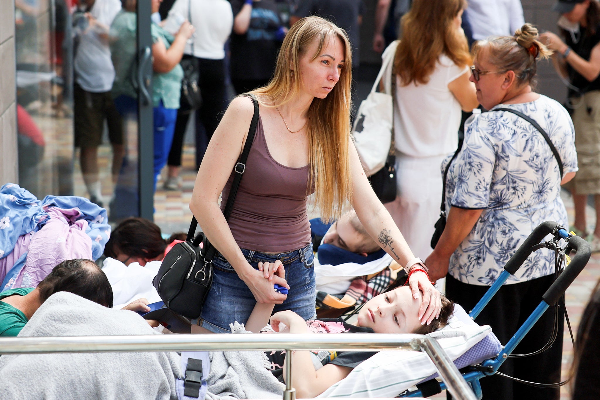 A woman touches a child near the Ohmatdyt Children's Hospital after it was damaged in a Russian attack.