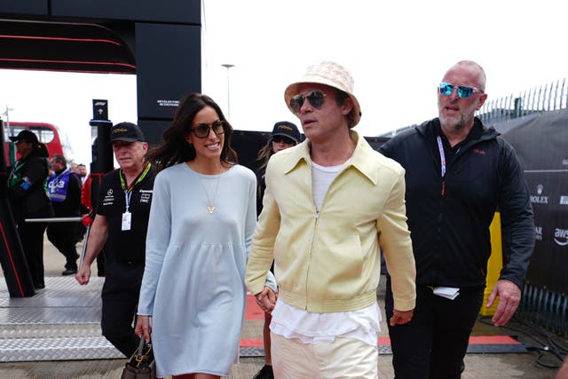Brad Pitt, 60, and Ines de Ramon, 34, arrive in primary pastel outfits at the British Grand Prix (David Davies/PA)