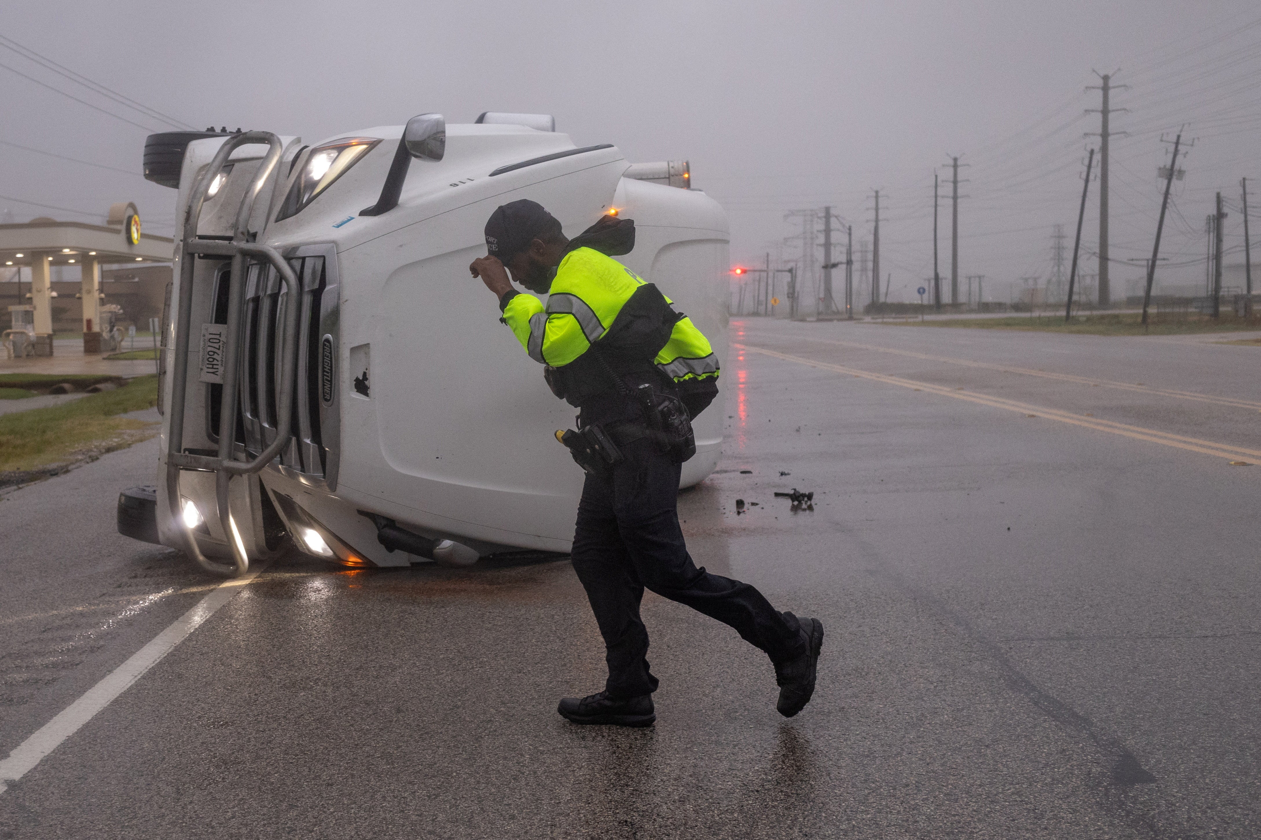 Ein Polizist kämpft gegen die starken Winde des Hurrikans Beryl, als er am 8. Juli 2024 in Freeport, Texas, USA, nach den Insassen eines umgestürzten Sattelzuges sucht.