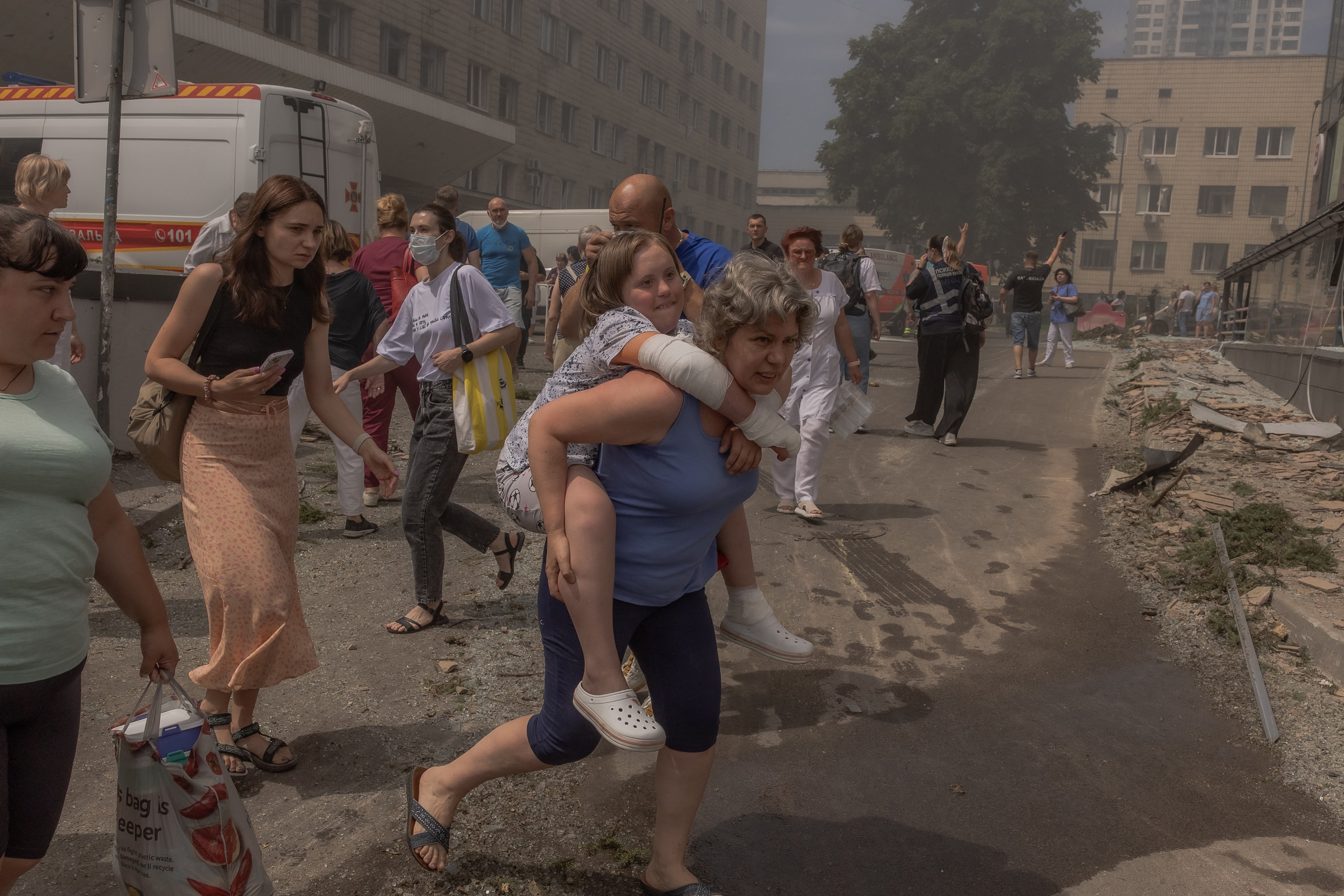 A woman carries a girl from the Ohmatdyt Children's Hospital