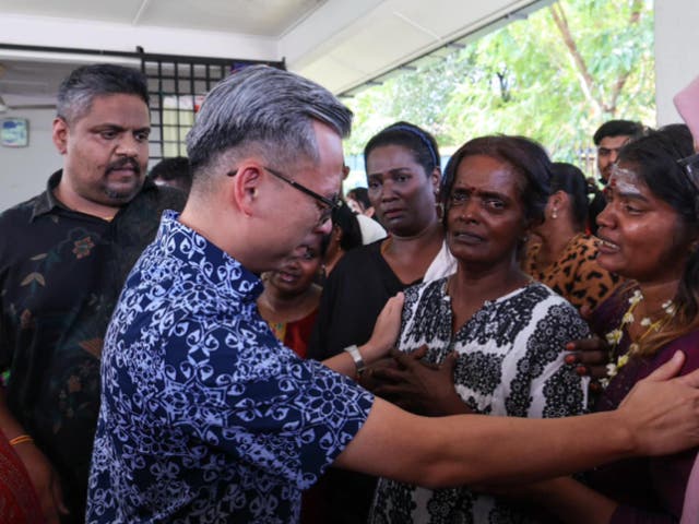 <p>Malaysia’s communications minister Fahmi Fadzil, dressed in blue, speaks with Rajeswary Appahu’s mother, who is in white, at the social media influencer’s funeral in Gombak, Selangor on 7 July 2024</p>
