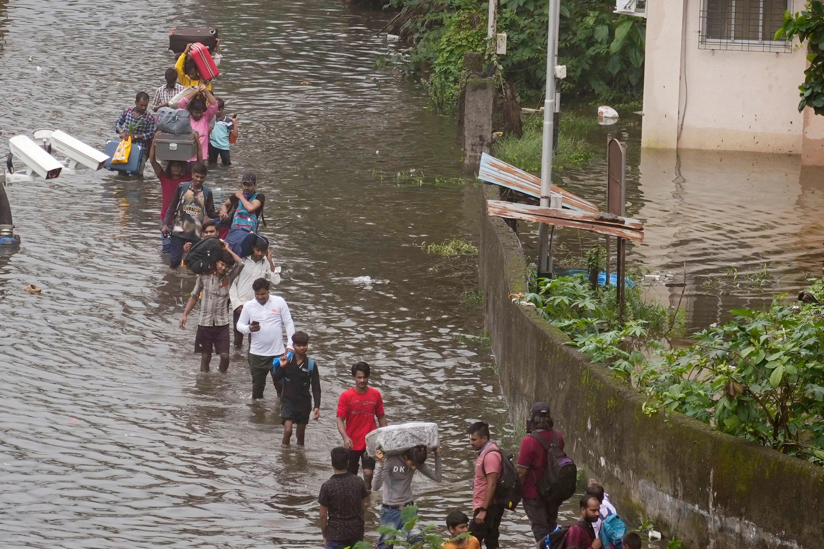 Commuters navigate a submerged street after heavy rainfall in Mumbai, India