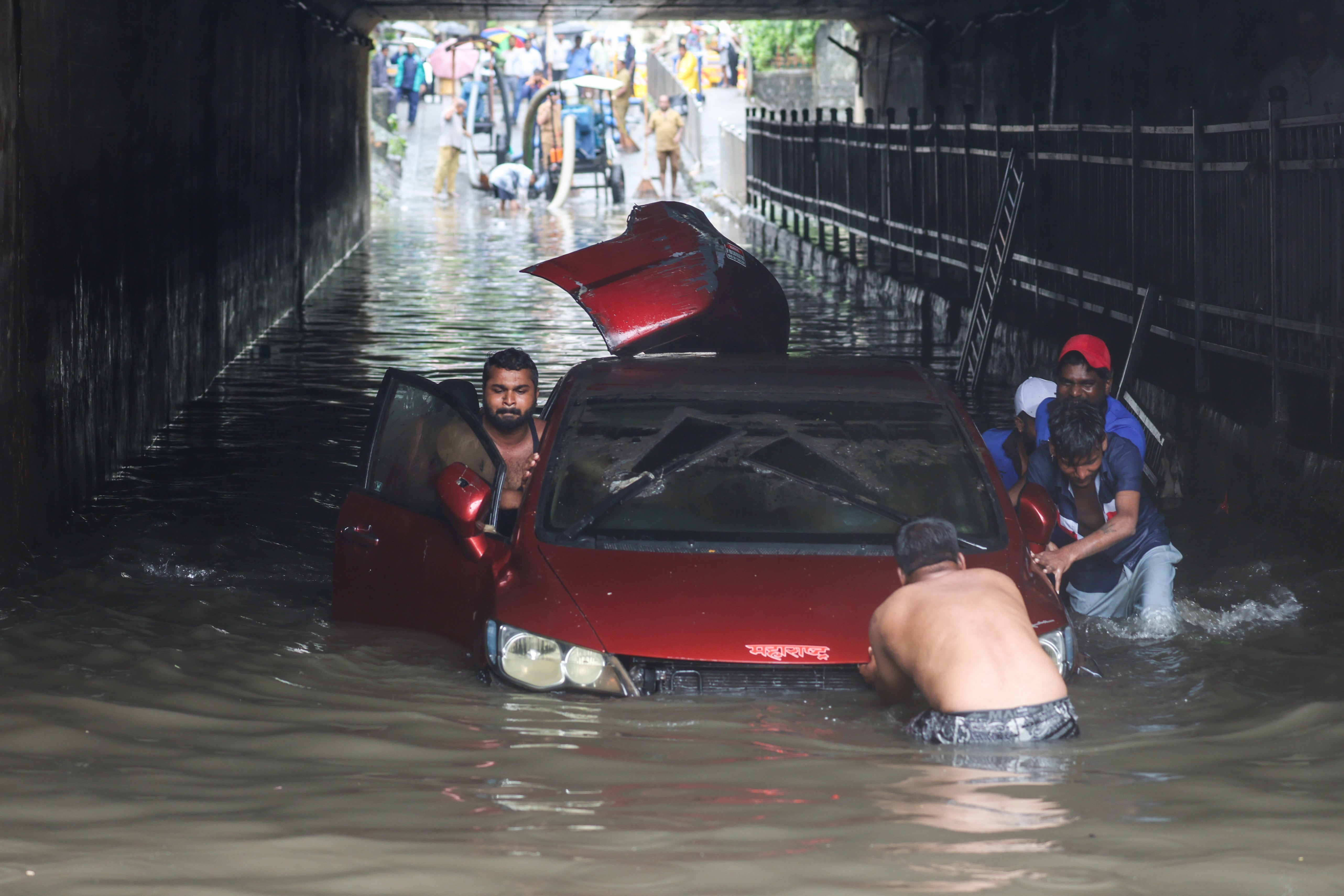 People push a stalled car in a flooded underpass during heavy rainfall in Mumbai