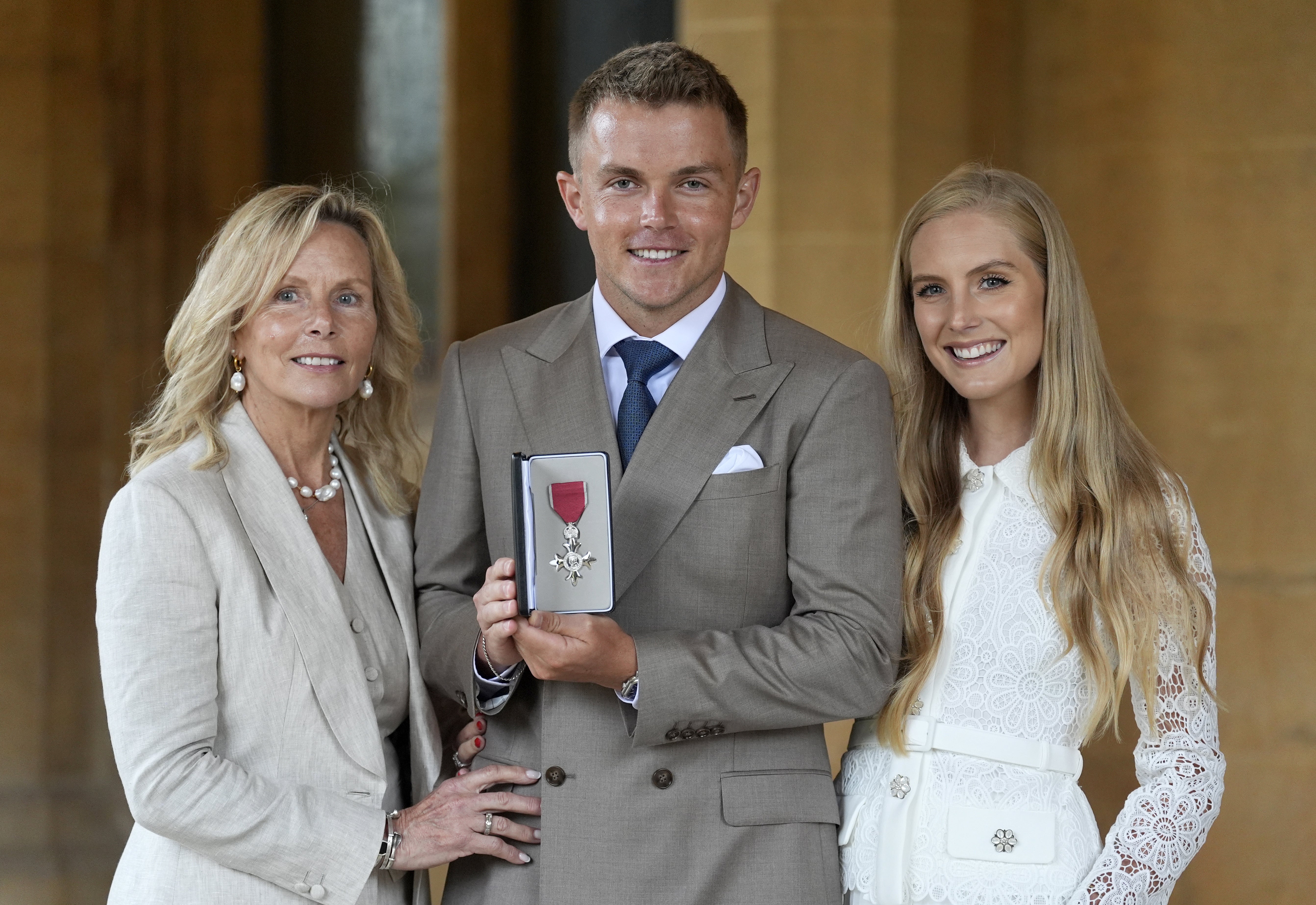 Sam Curran with his mother Sarah (left) and partner Isabella after being made a Member of the Order of the British Empire by the King (Andrew Matthews/PA)