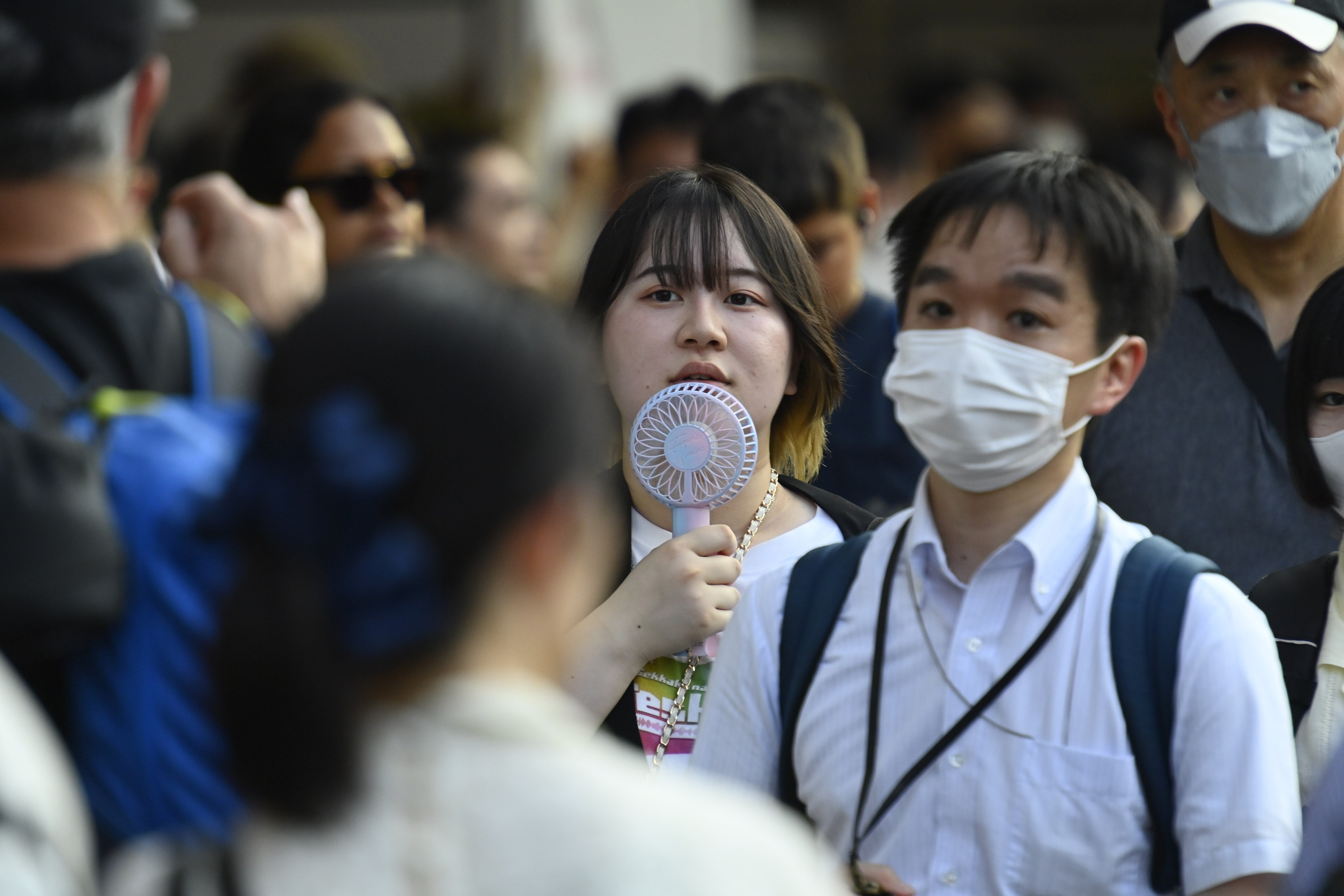 A young woman walks on the street using a handheld fan in the late of afternoon on July 5, 2024, in Tokyo, Japan