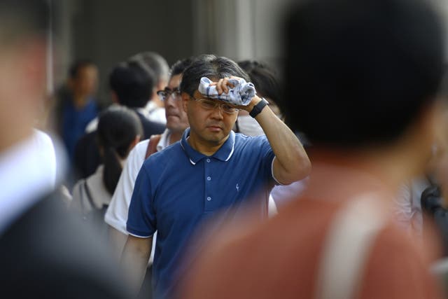 <p>File. A man walking down the street after work wipes sweat from his forehead in Tokyo, Japan, on 5 July 2024</p>