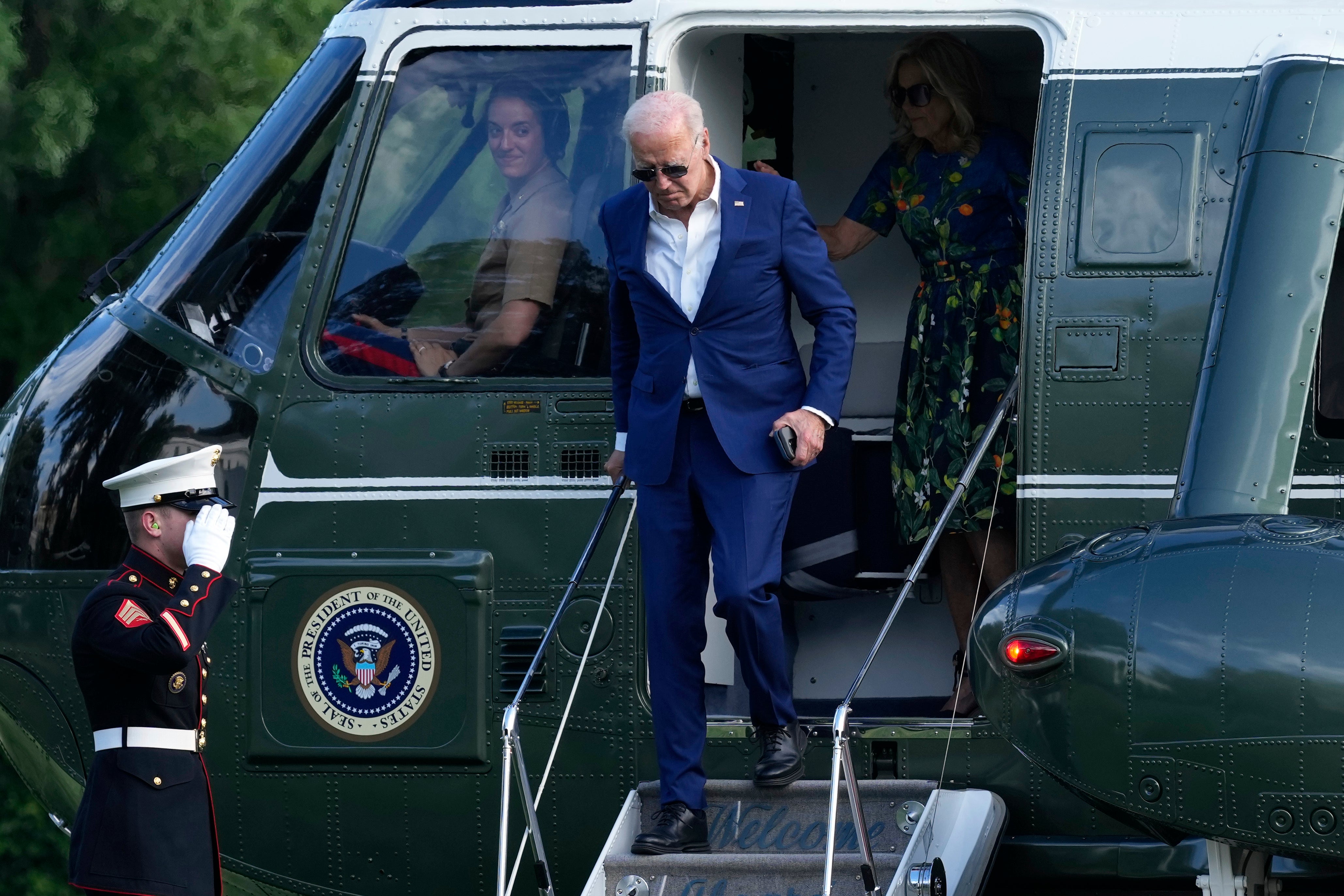President Joe Biden, center, and first lady Jill Biden, right, walk off of Marine One on the South Lawn of the White House in Washington