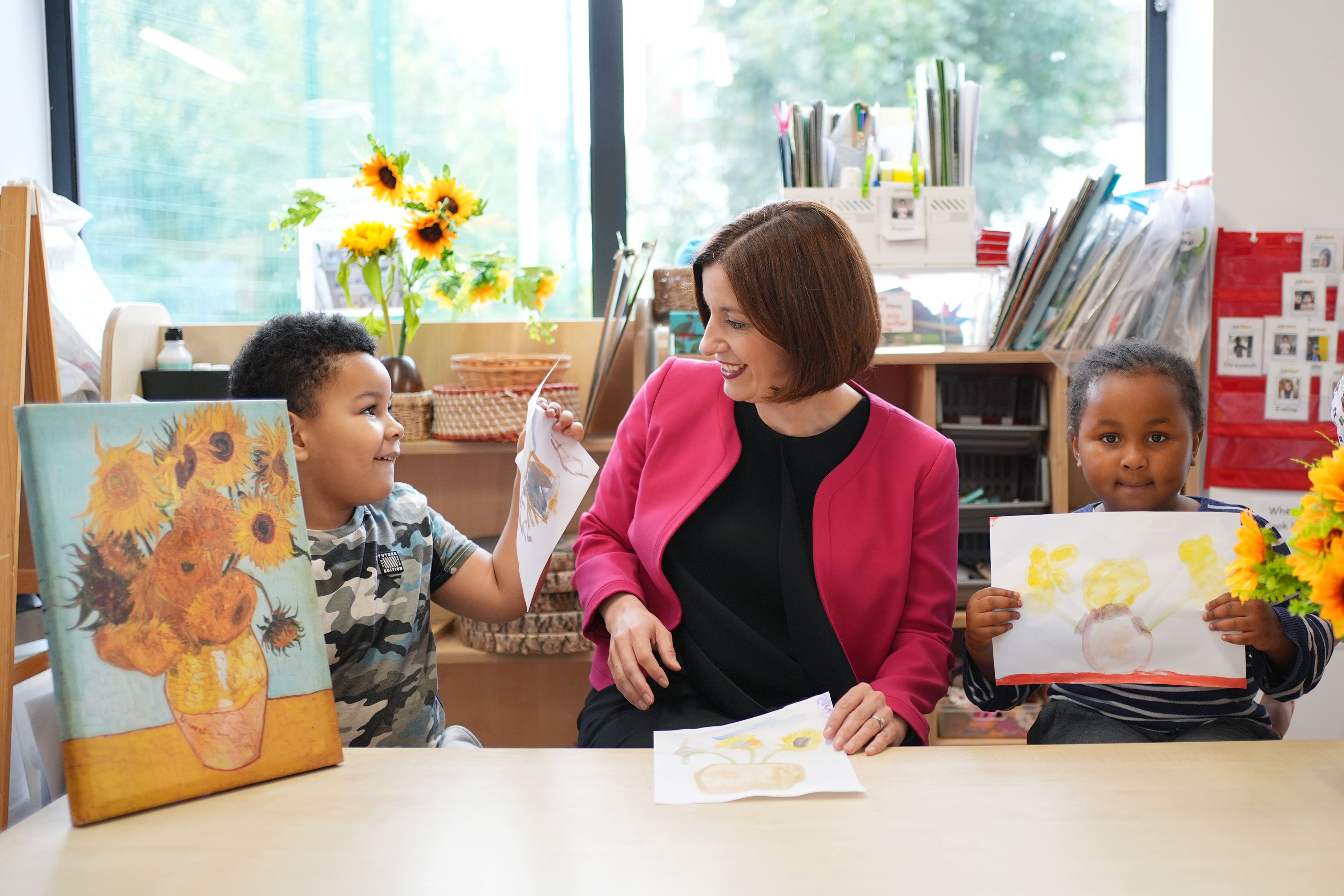 Education Secretary Bridget Phillipson with her painting of sunflowers, alongside pupils Wyatt, aged 4 (left), and Aicha, aged 4, during a visit to the school-based nursery at Ark Start Oval, East Croydon, in south London (Yui Mok/PA)