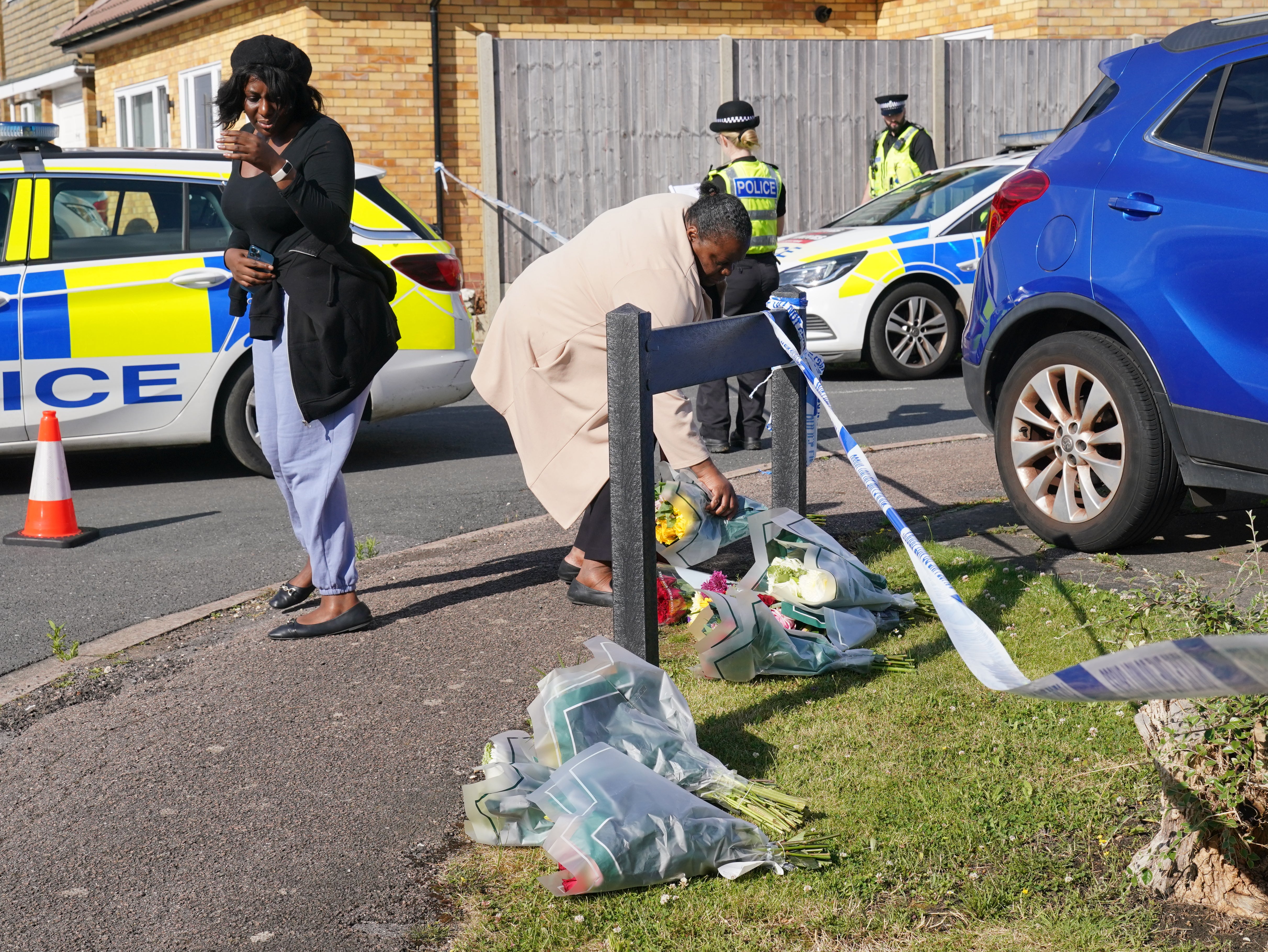 A woman delivers floral tributes near to the scene in Ashlyn Close, Bushey, Hertfordshire