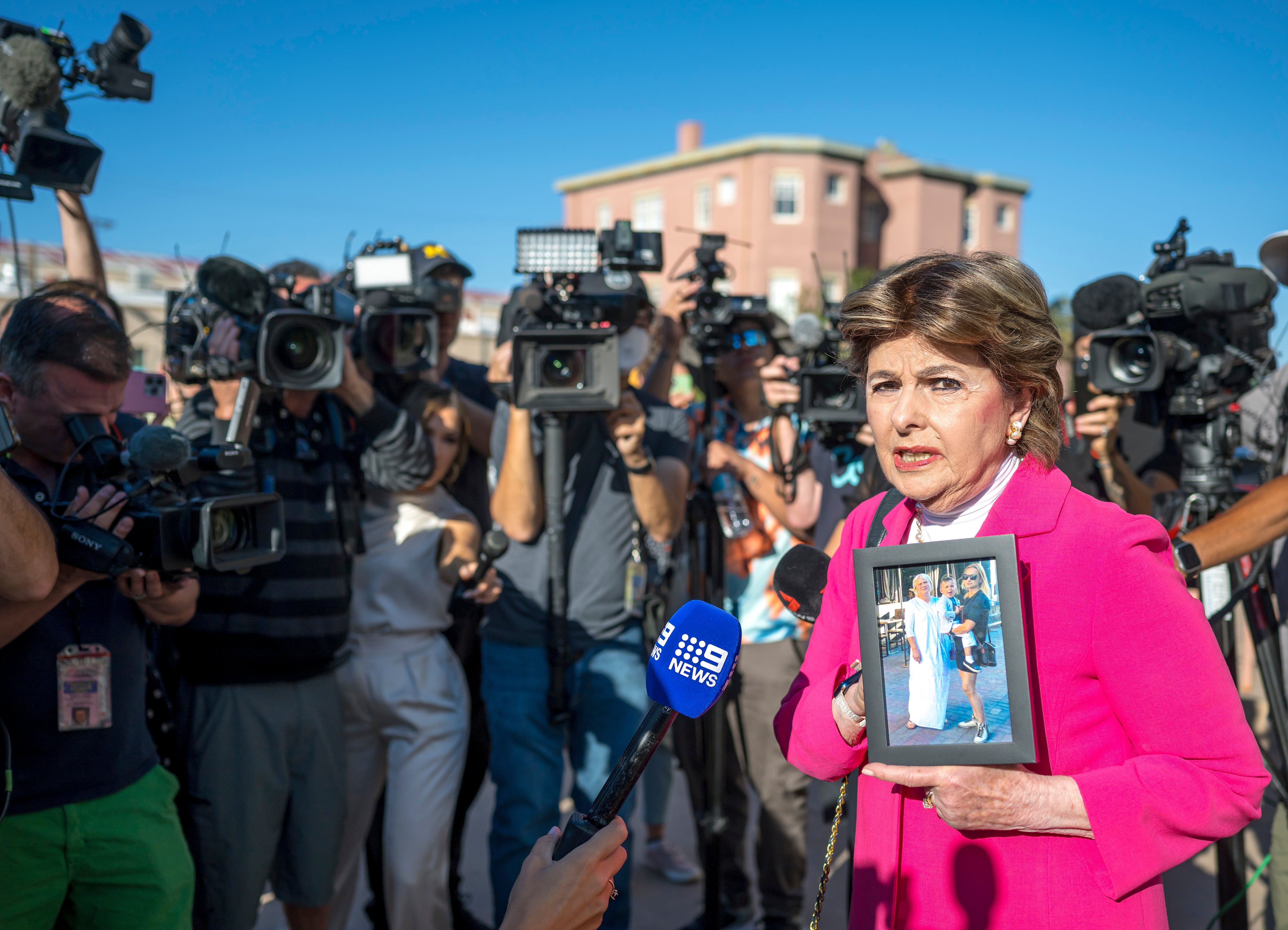 Attorney Gloria Allred holds a picture of Halyna Hutchins outside a District Court