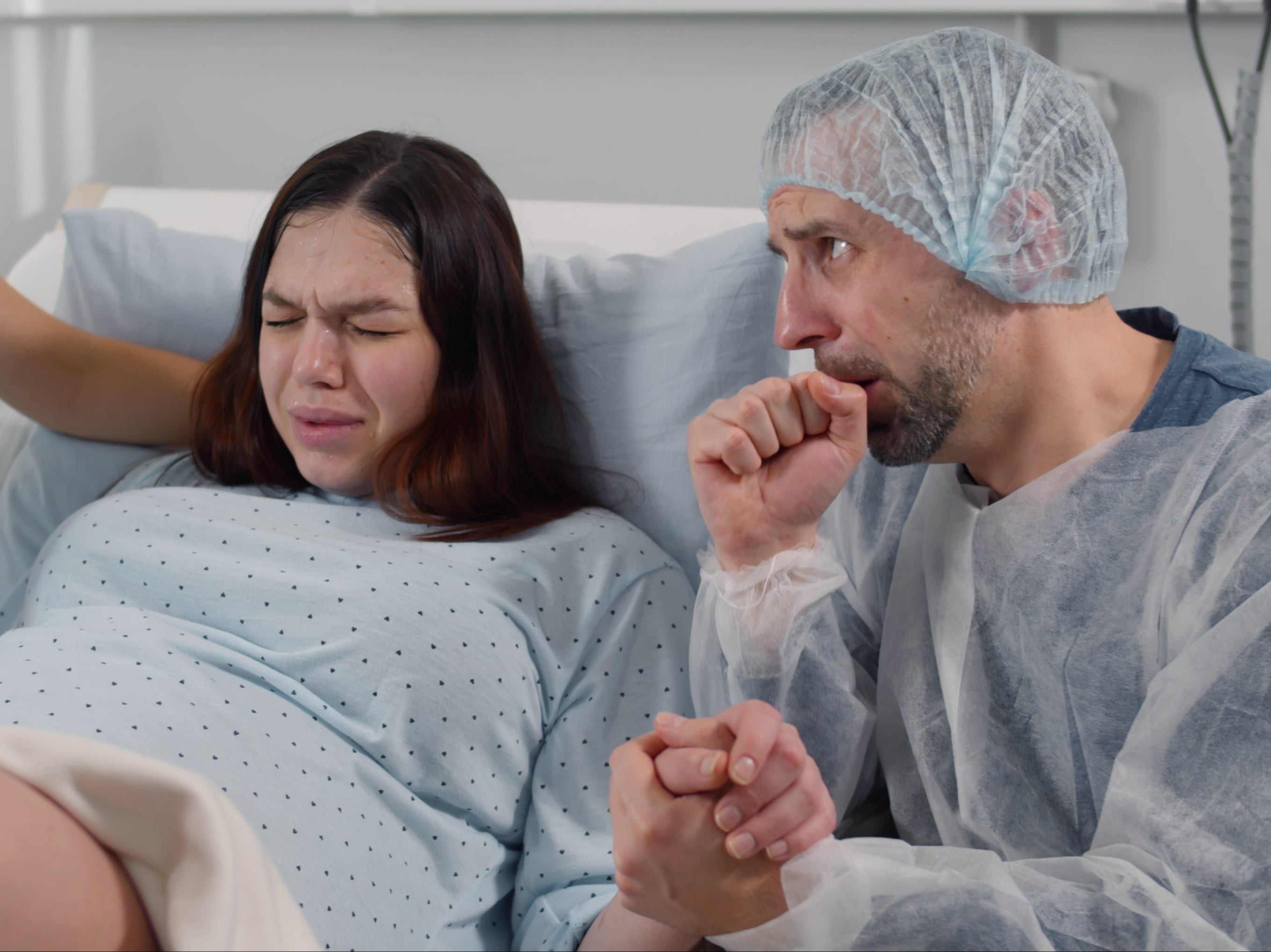 Scared husband holding hands and supporting wife in labor ( Getty Images )