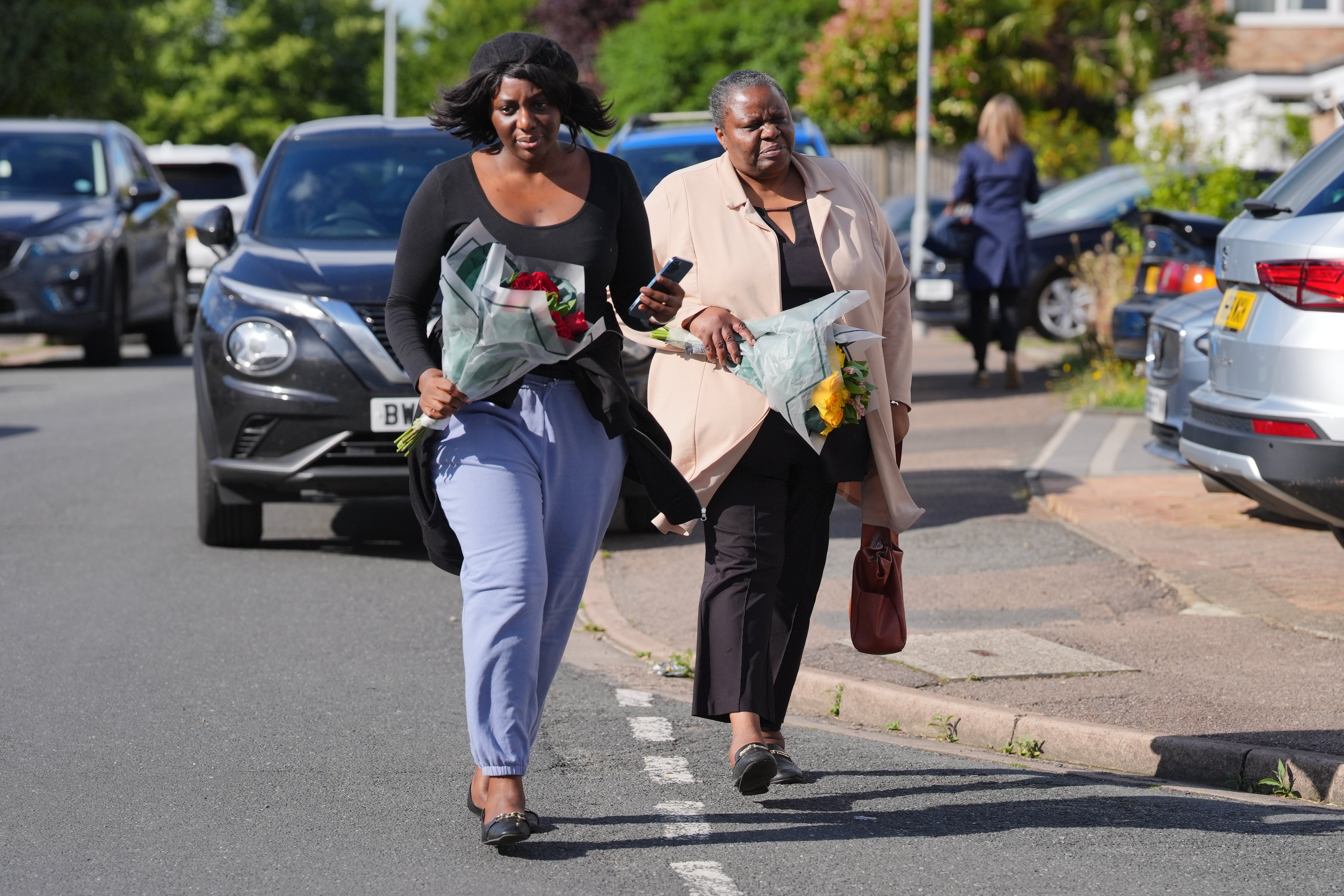 Two women deliver floral tributes near to the scene in Ashlyn Close, Bushey, Hertfordshire, where the wife and two daughters of a BBC sports commentator have been killed in a crossbow attack at their home