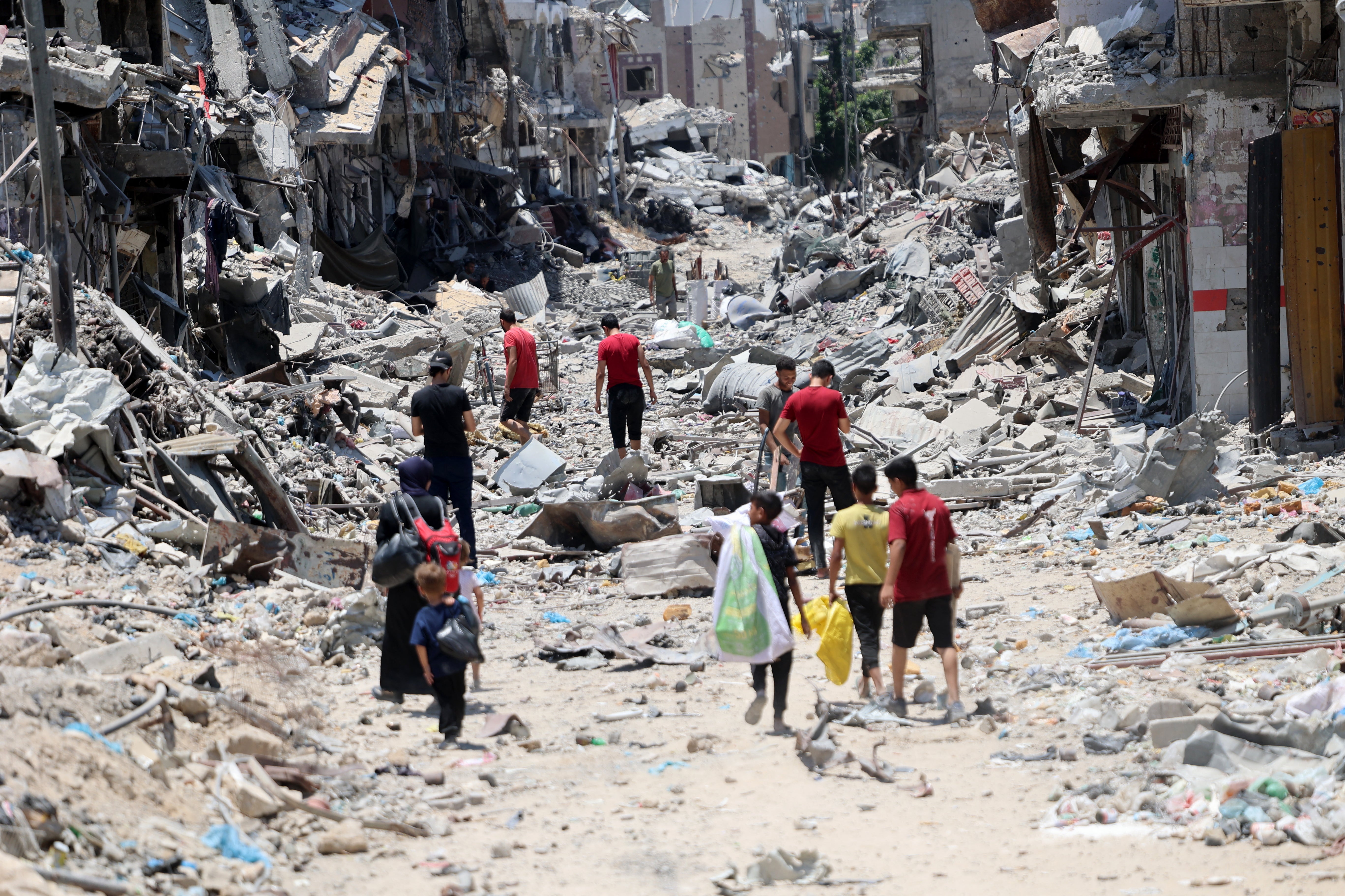 Palestinian men, a woman and children, make their way over rubble