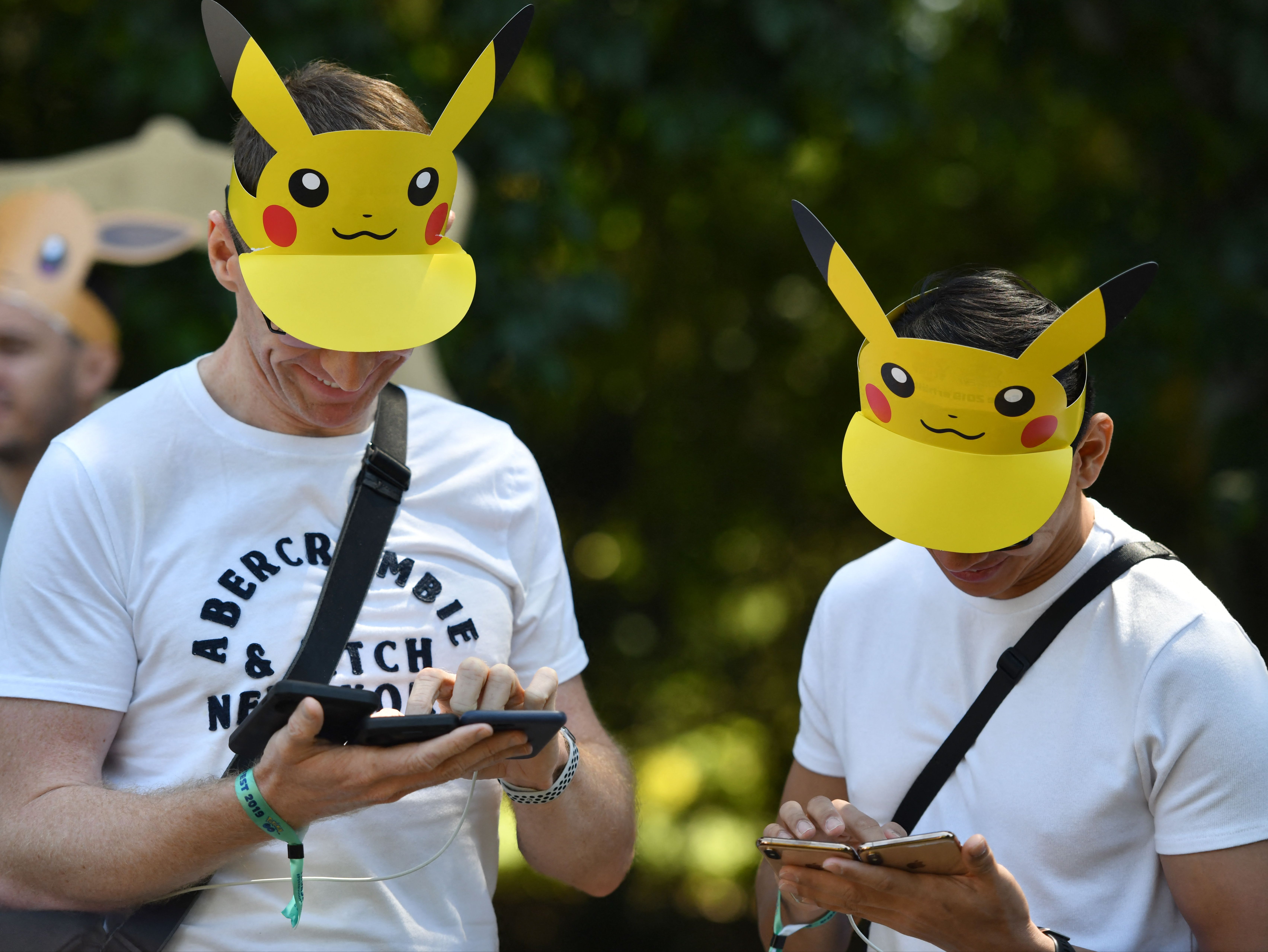 Visitors, with Pokemon caps, look at their phones during the Pokemon Go Festival on 4 July 2019 at the Westfalenpark in Dortmund, western Germany