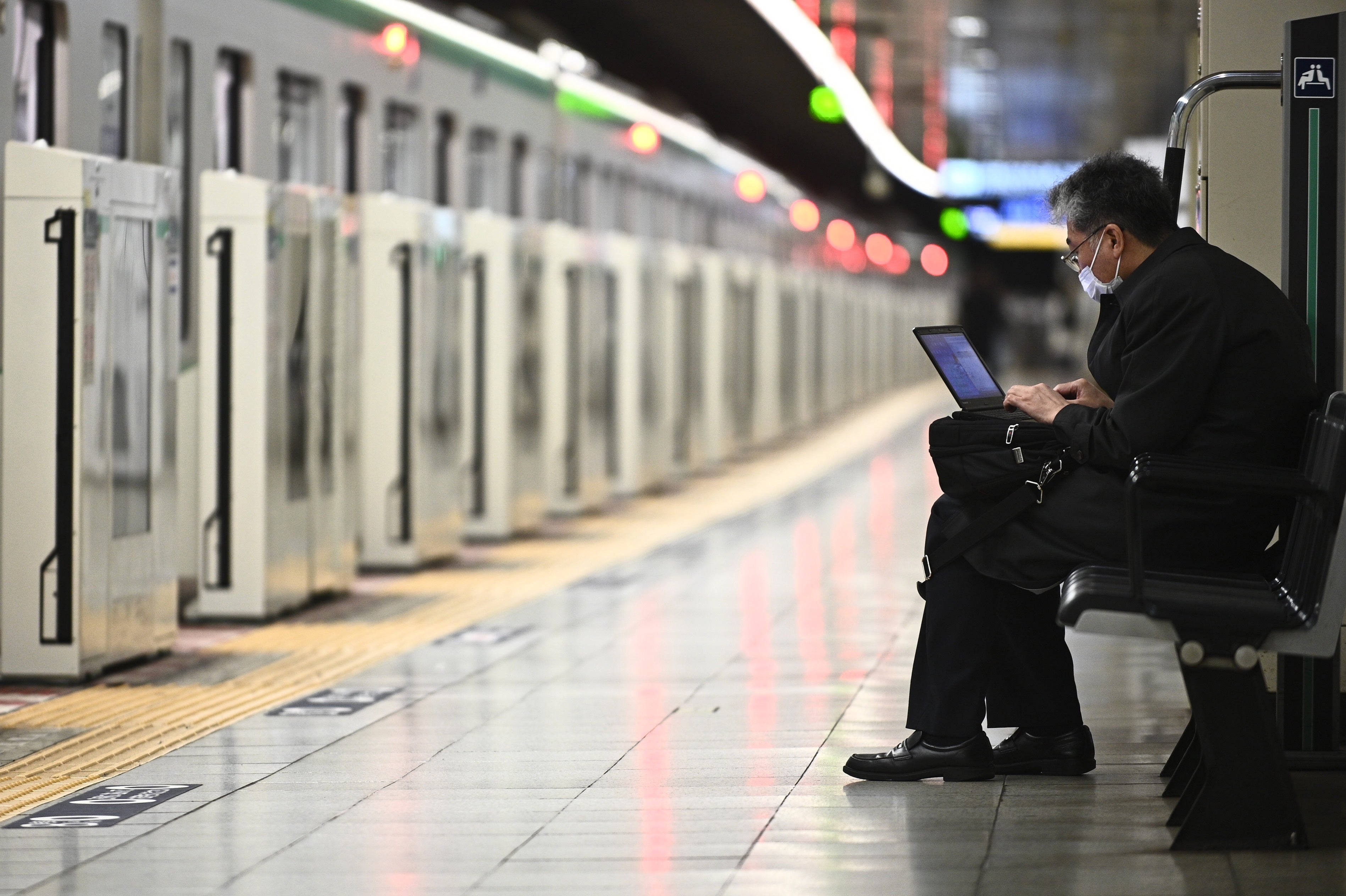 Representational. A man works on his laptop at a train station in China