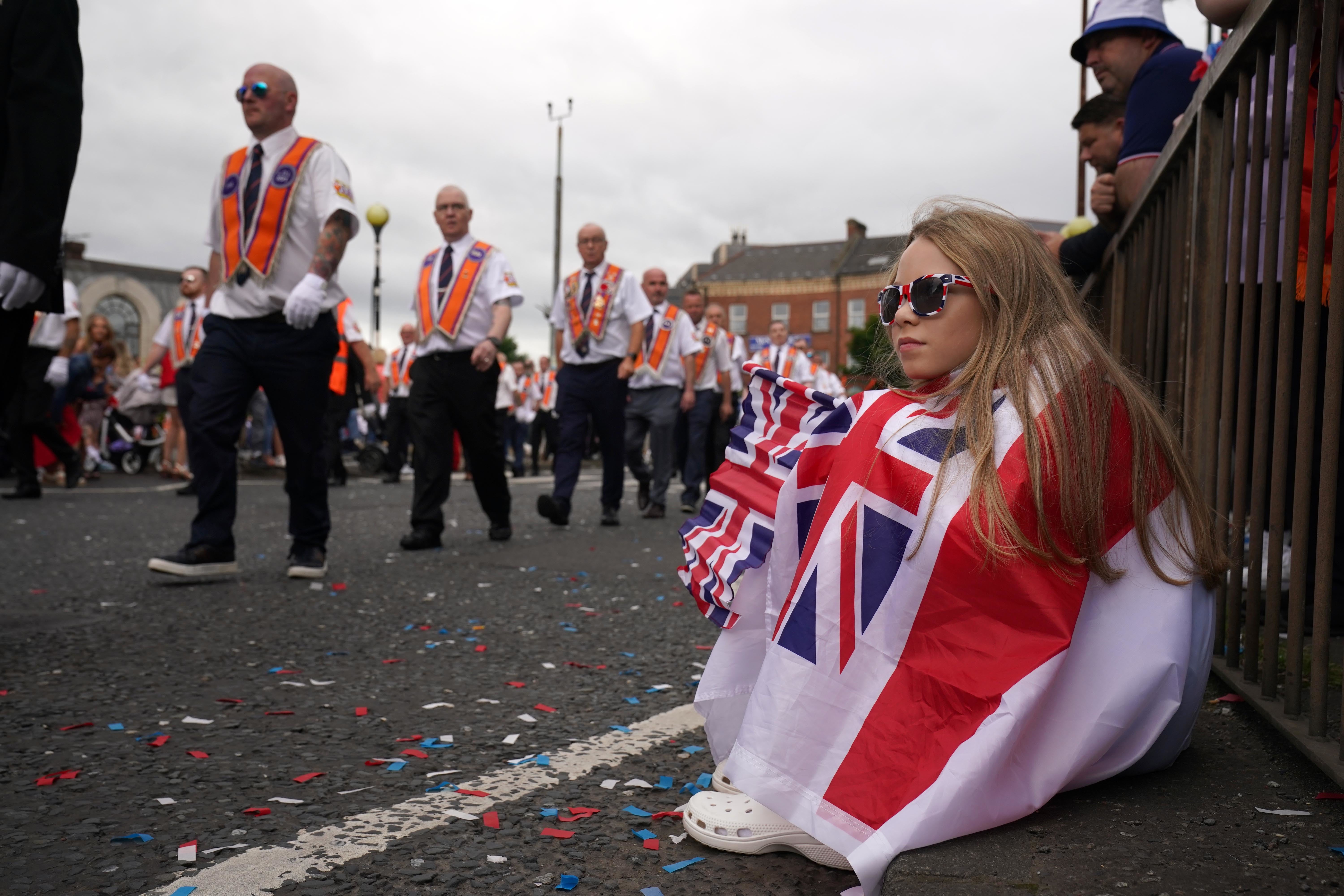 Grace Moffett, aged 11, was draped in a flag as she watched Orange Order members march past (Brian Lawless/PA)
