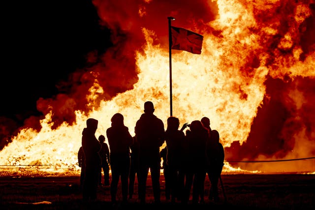 Members of the public watch the burning pyre at the Craigyhill eleventh night bonfire in Larne (Liam McBurney/PA)