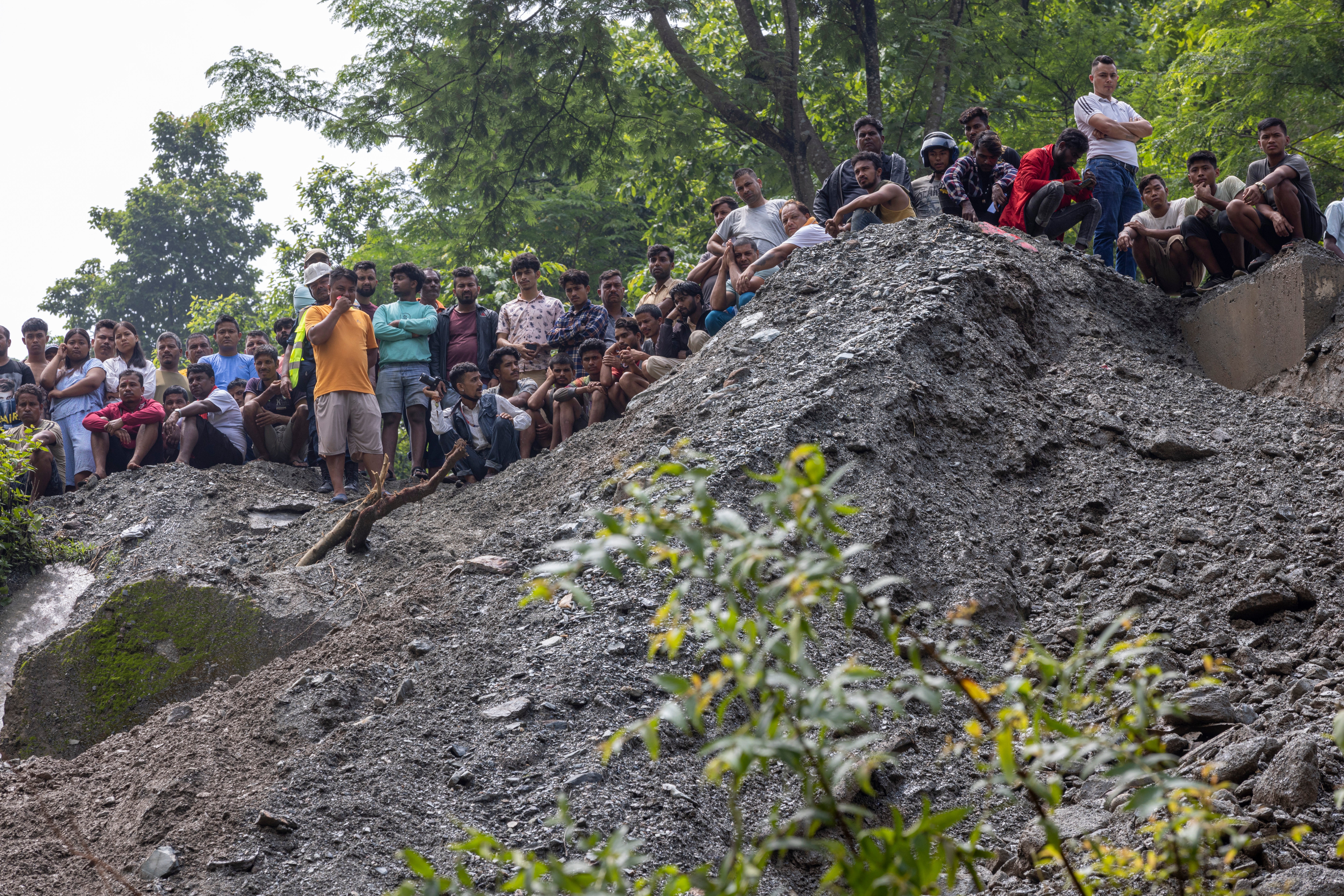 Family members gather while members of a rescue team conduct a search and rescue operation after two passenger buses were swept away by a landslide, at Trishuli River in Simaltal, Chitwan district