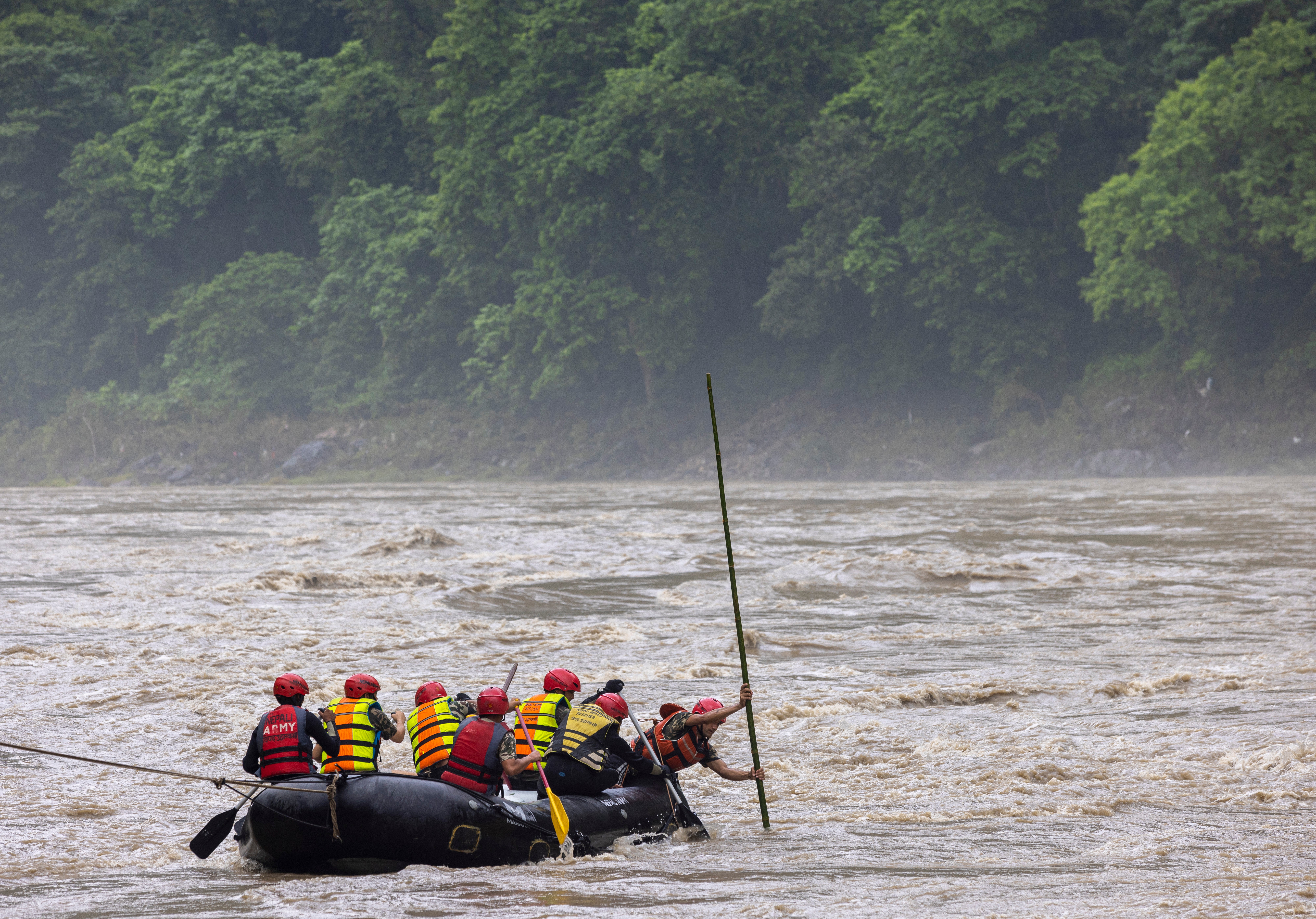 Members of a rescue team conduct a search and rescue operation after two passenger buses were swept away by a landslide, at Trishuli River in Simaltal, Chitwan district, Nepal