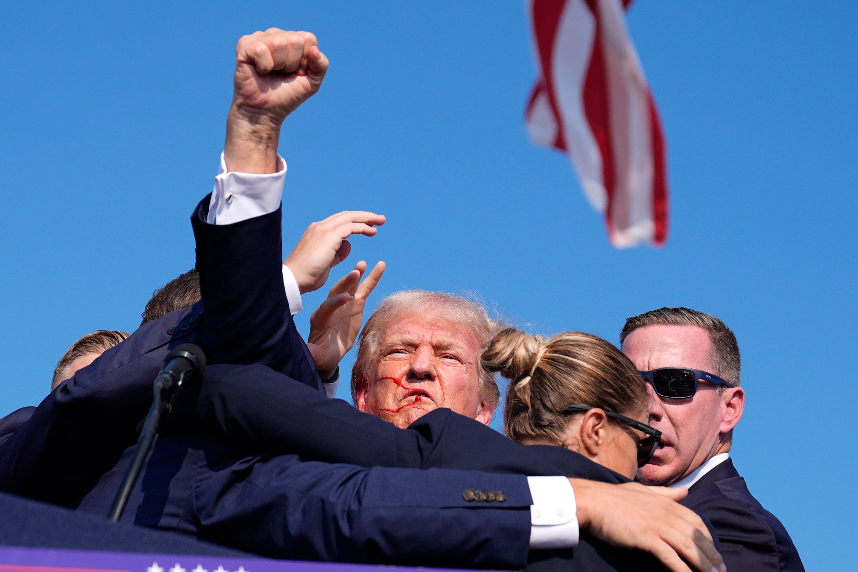 The former president fistpumped the air as he was escorted off the stage by the agents and taken to a nearby medical center