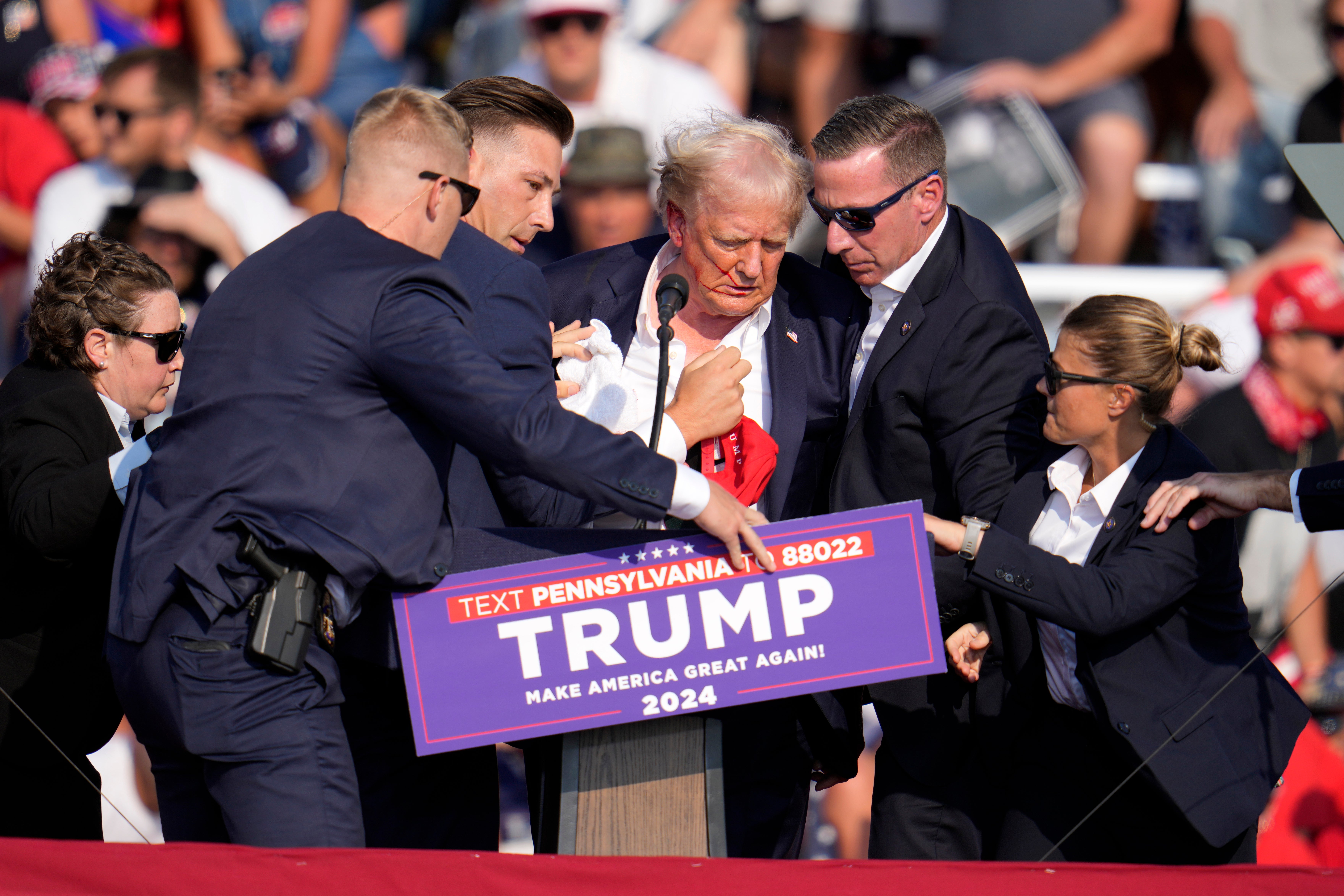 Donald Trump is helped off the stage at the campaign event in Butler