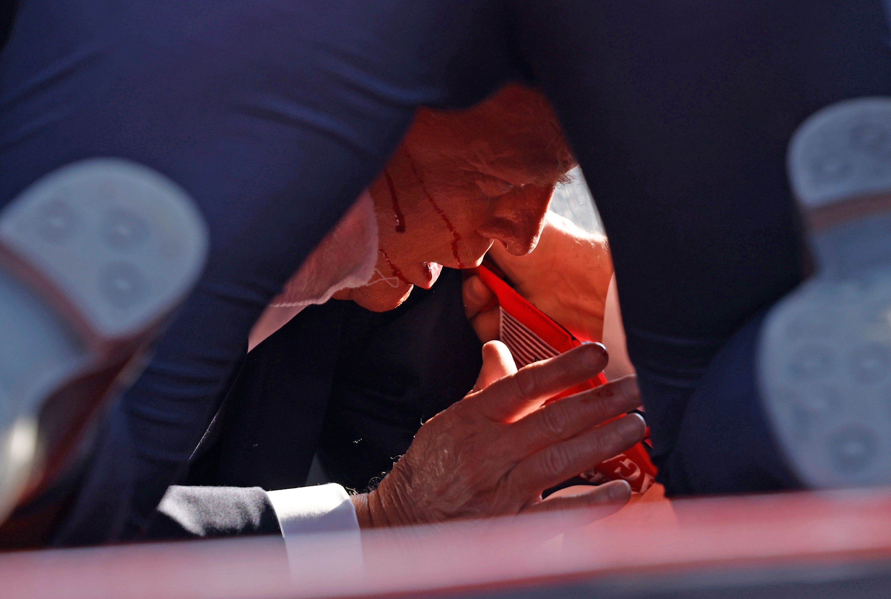 Trump is pictured on the ground with his security detail on top of him after shots were heard