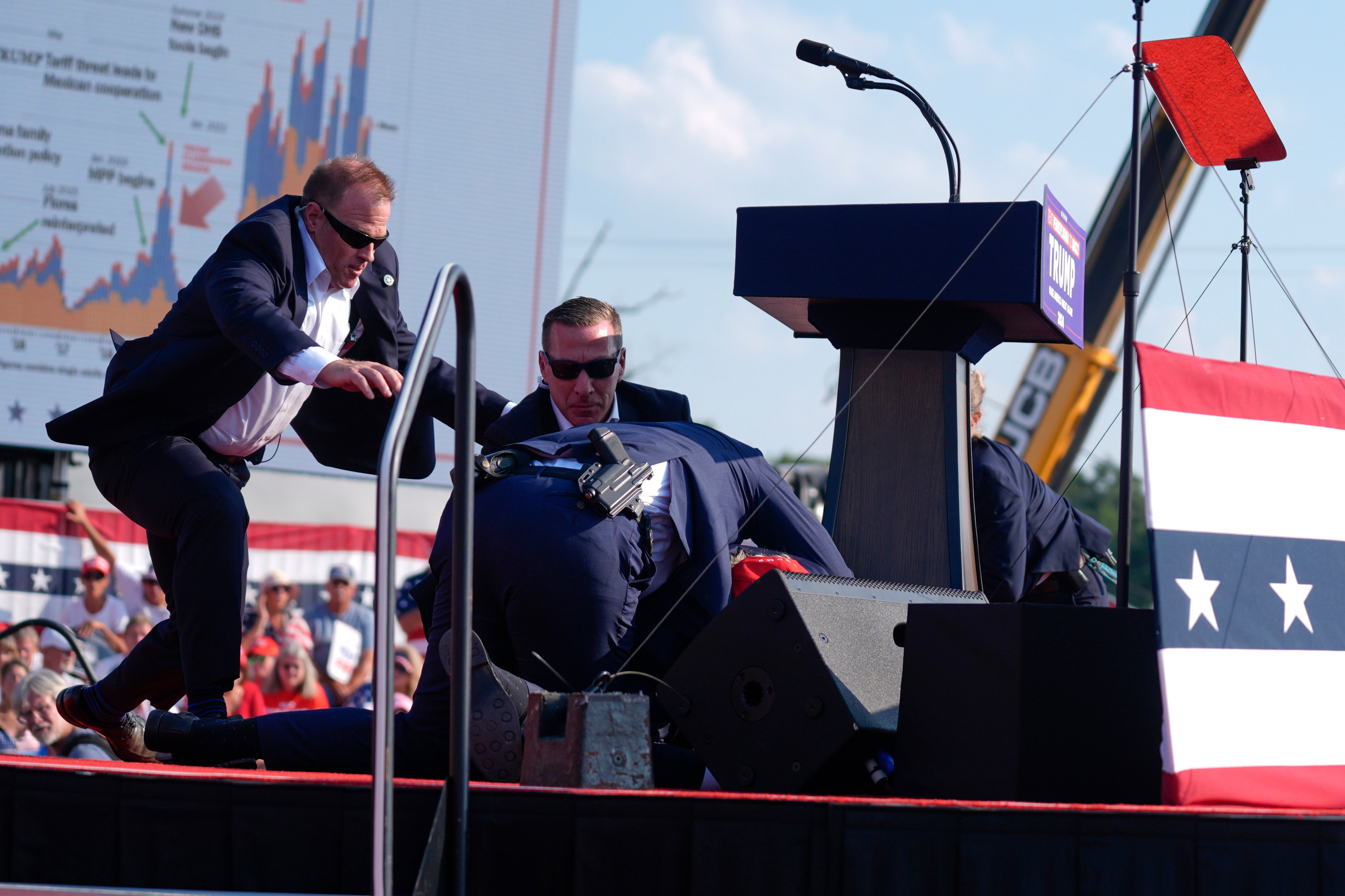 Secret Service agents converged to cover the Republican presidential candidate. The sounds came from the left of where Trump was standing