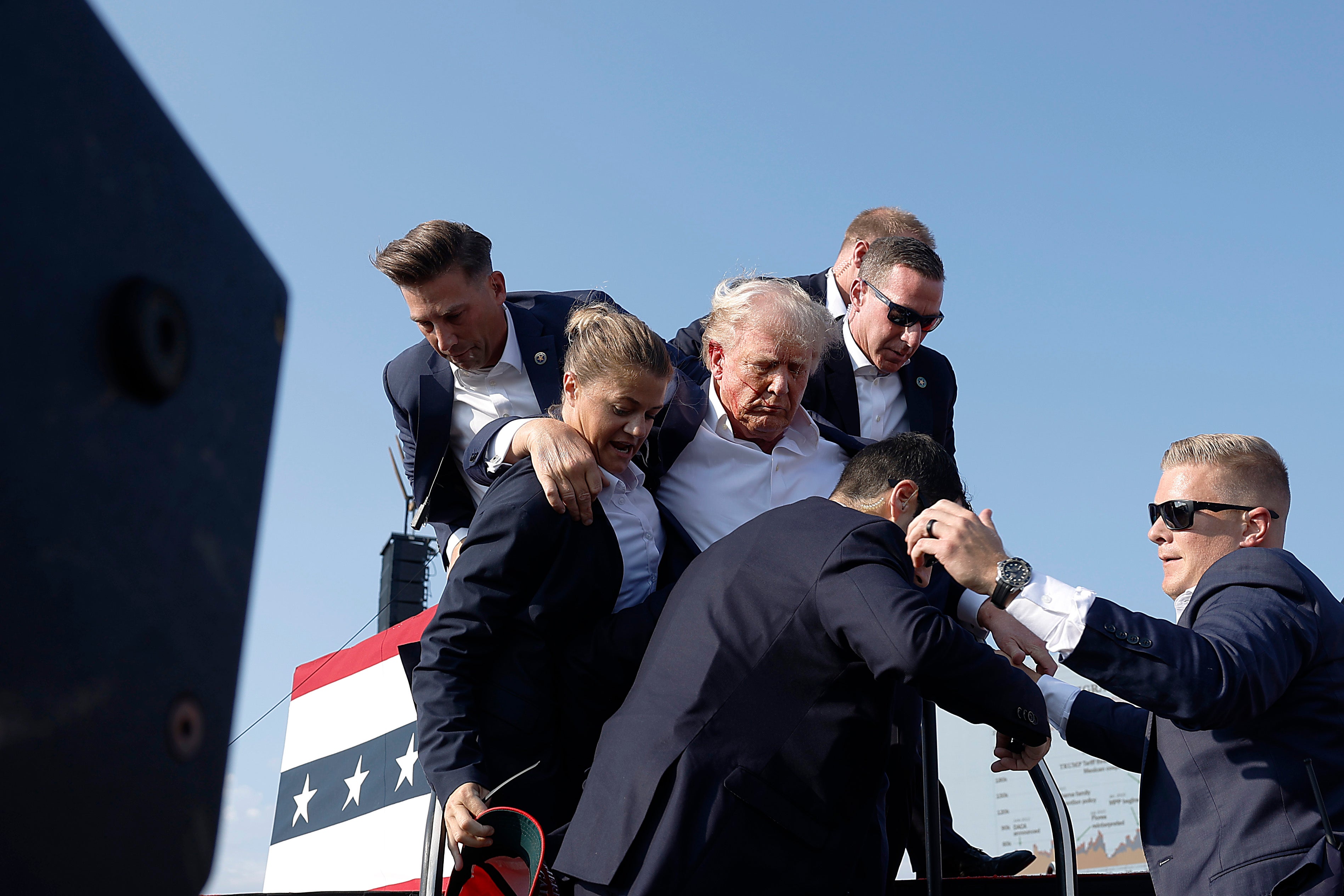 O ex-presidente Donald Trump levanta o punho ao ser levado para fora do palco durante um comício em 13 de julho de 2024 em Butler, Pensilvânia