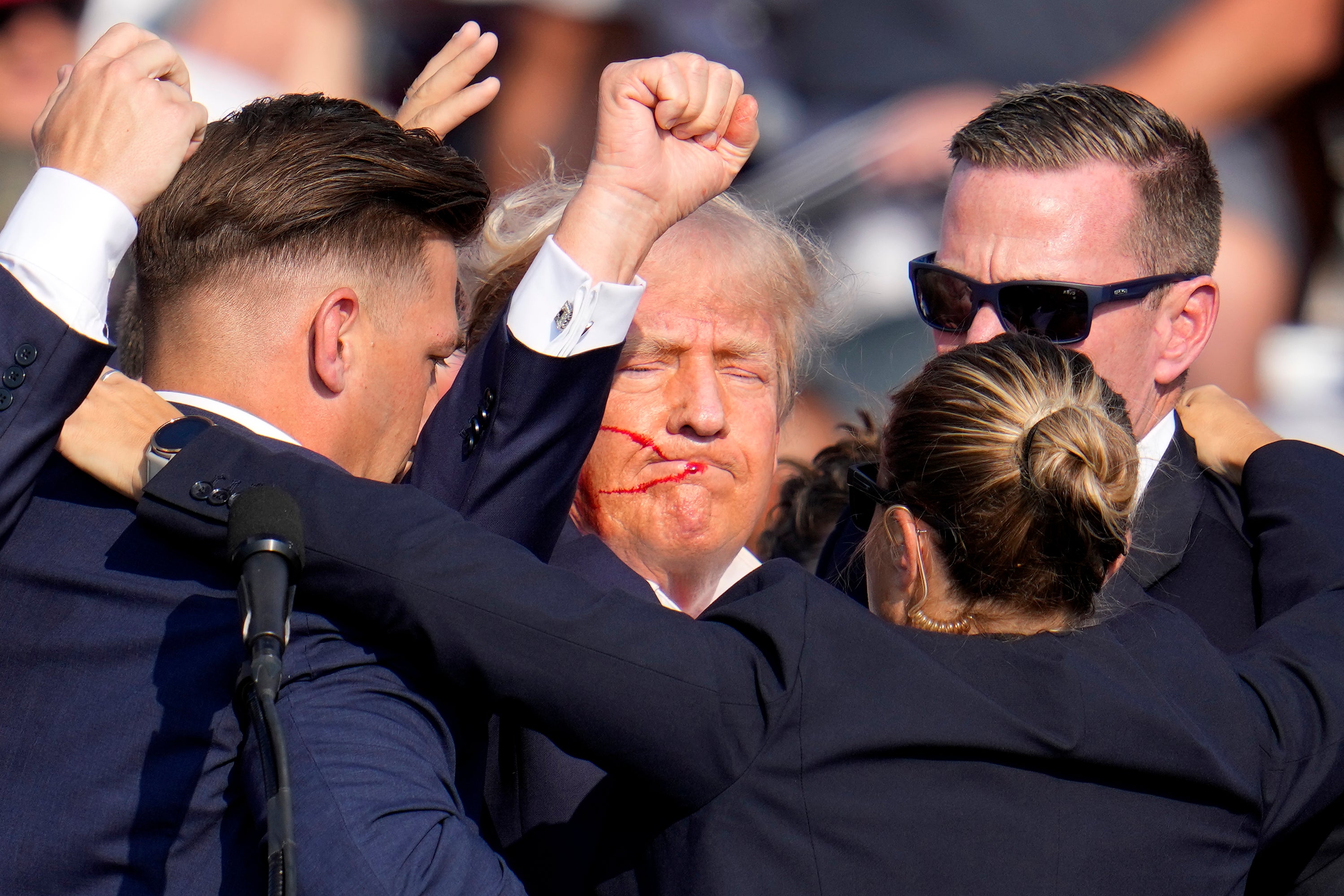 Former president Donald Trump pumps his fist as he is helped off the stage by US Secret Service agents after the assassination attempt (Gene J Puskar/AP)