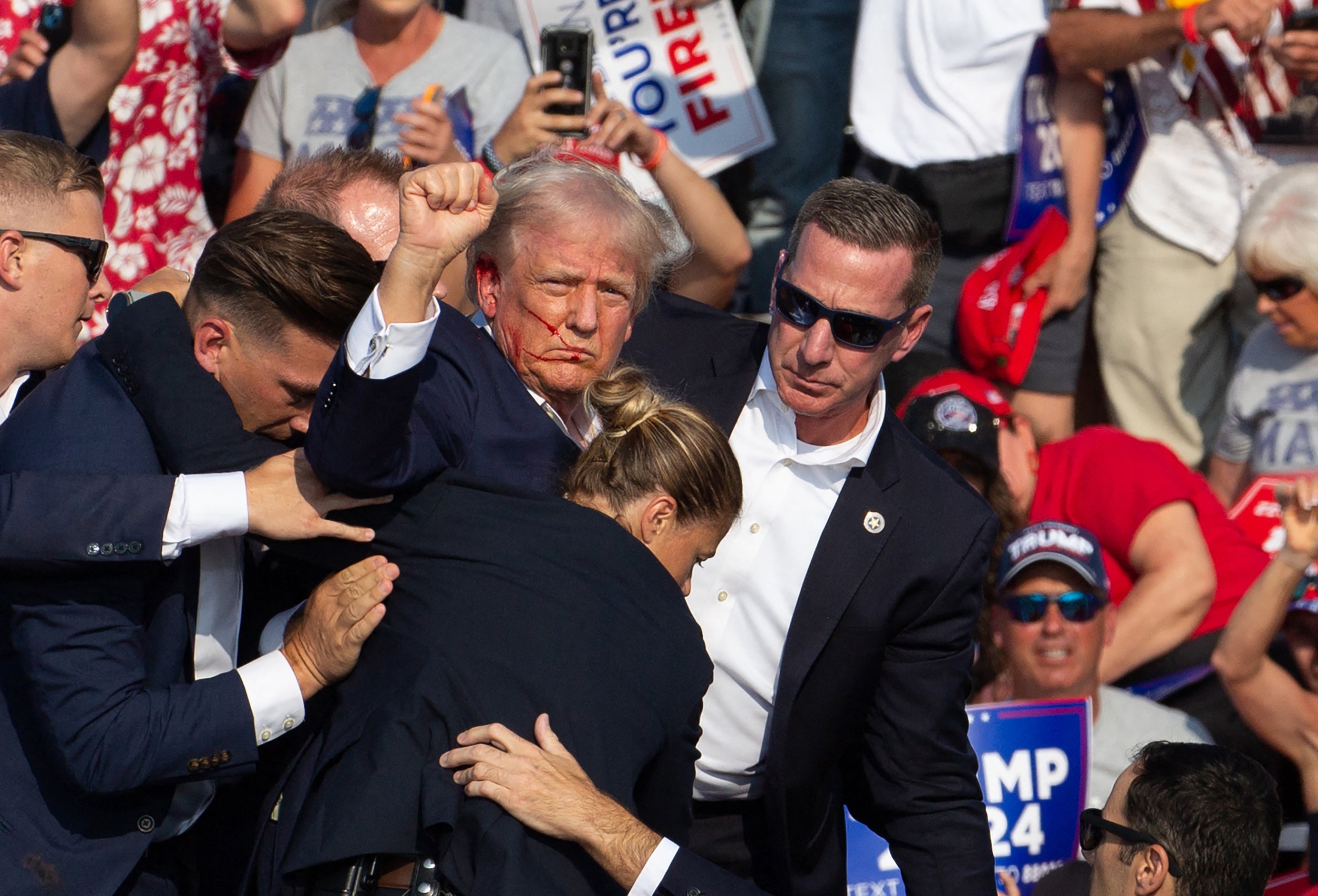 Trump pumped his fist in the air as Secret Service staff took him towards his car