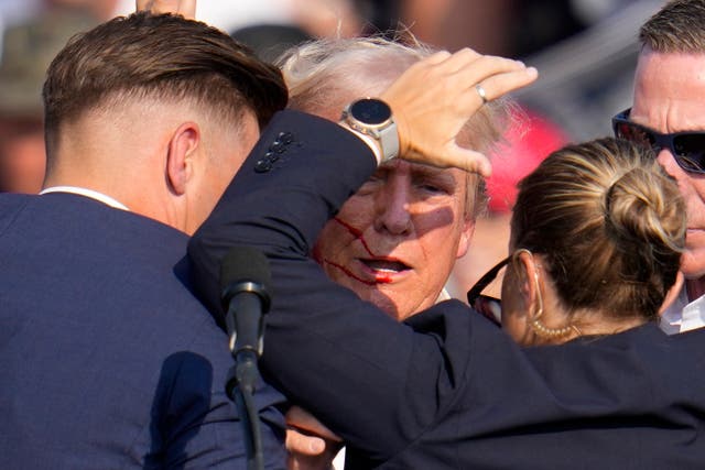 <p>Former president Donald Trump is helped off stage by Secret Service agents. A witness said Trump was just inches from being killed in the shooting </p>