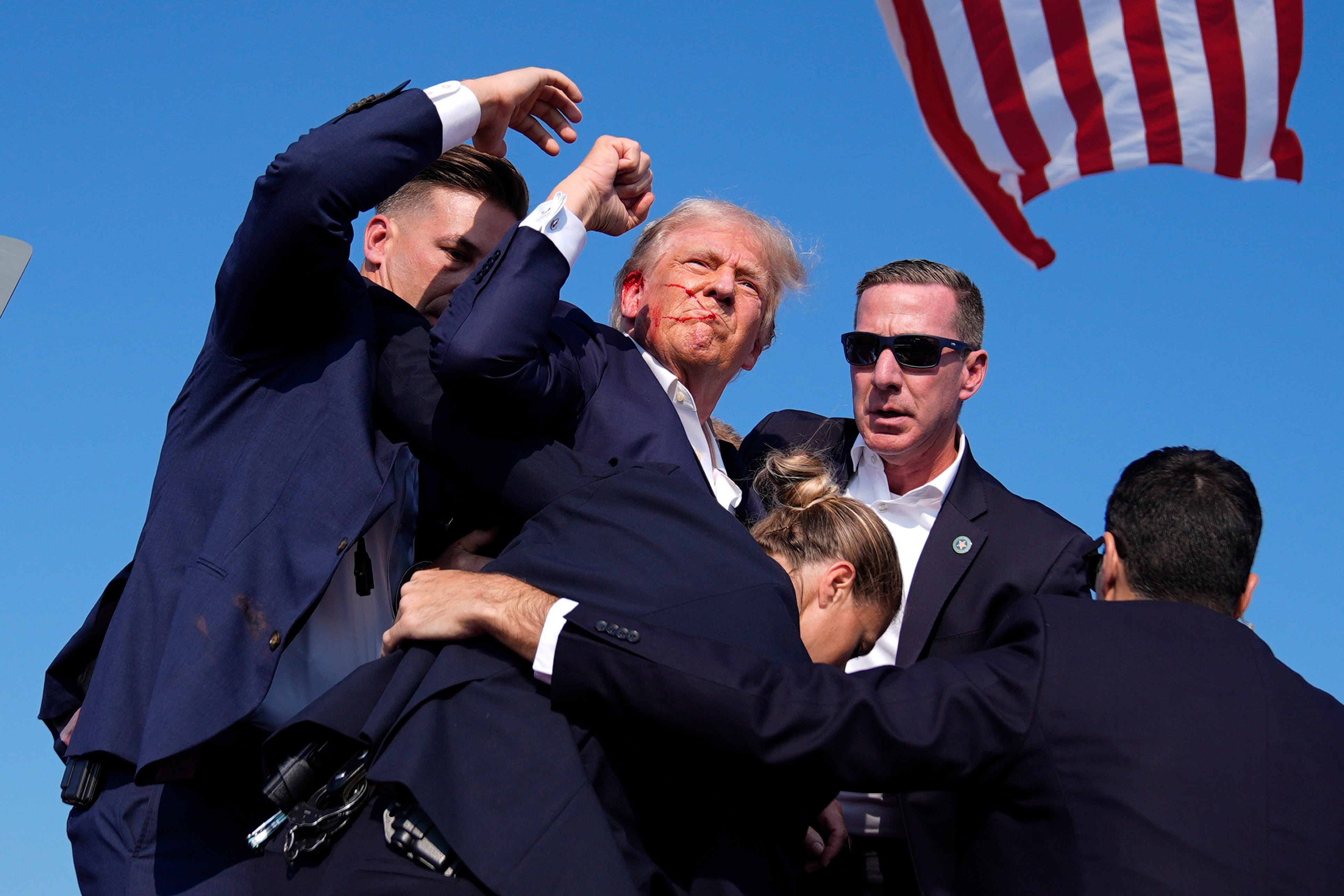 Trump raises his fist in the air to show he's OK after an assassination attempt was made at his campaign rally in Butler, Pennsylvania. A GoFundMe campaign he authorized has raised nearly $2 million for the victims.