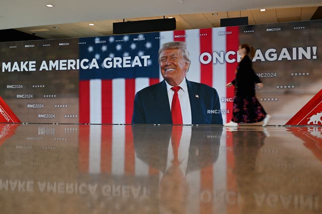 <p>A person walks past a “Make America Great Once Again!” poster ahead of the 2024 Republican Convention (RNC) at the Fiserv Forum in Milwaukee, Wisconsin, on July 14, 2024</p>