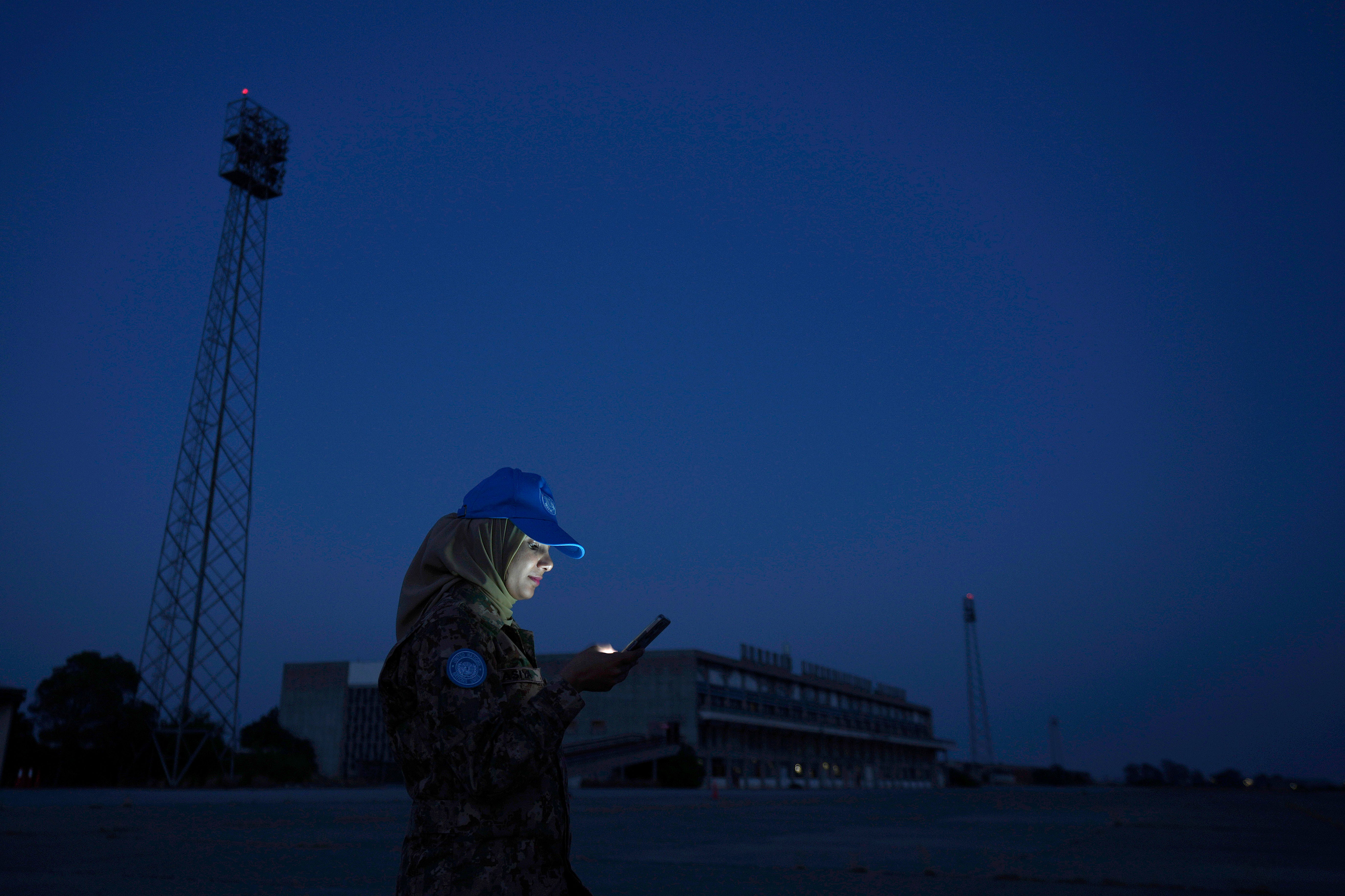 A U.N. peacekeeper use her cell phone as she stands in front of the the abandoned Nicosia airport