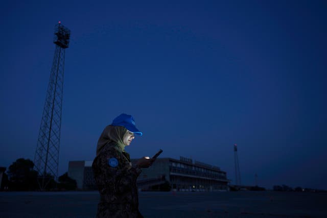 <p>A U.N. peacekeeper use her cell phone as she stands in front of the the abandoned Nicosia airport</p>