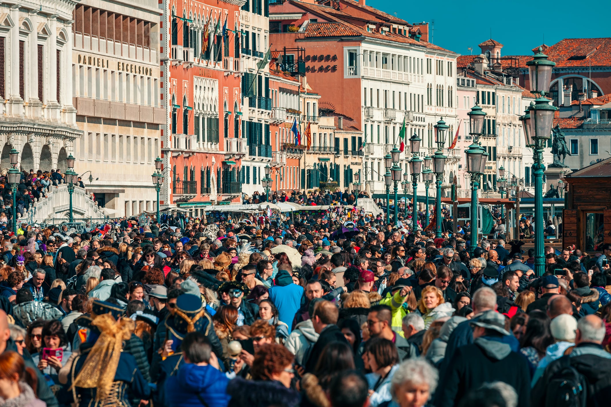 Crowds of tourists walking by typical venetian buildings near San Marco Square during famous traditional carnival taking place each year in Venice, Italy